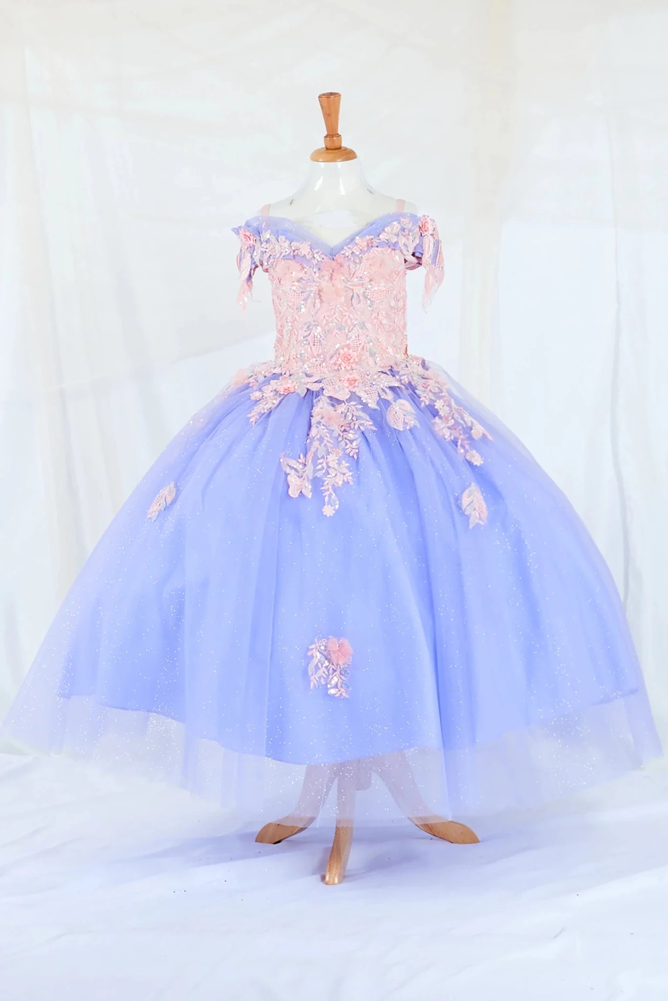 Front-facing display of a glamorous Bahama blue ball gown featuring a glitter-embroidered bodice, beaded sleeves, and a voluminous layered skirt.