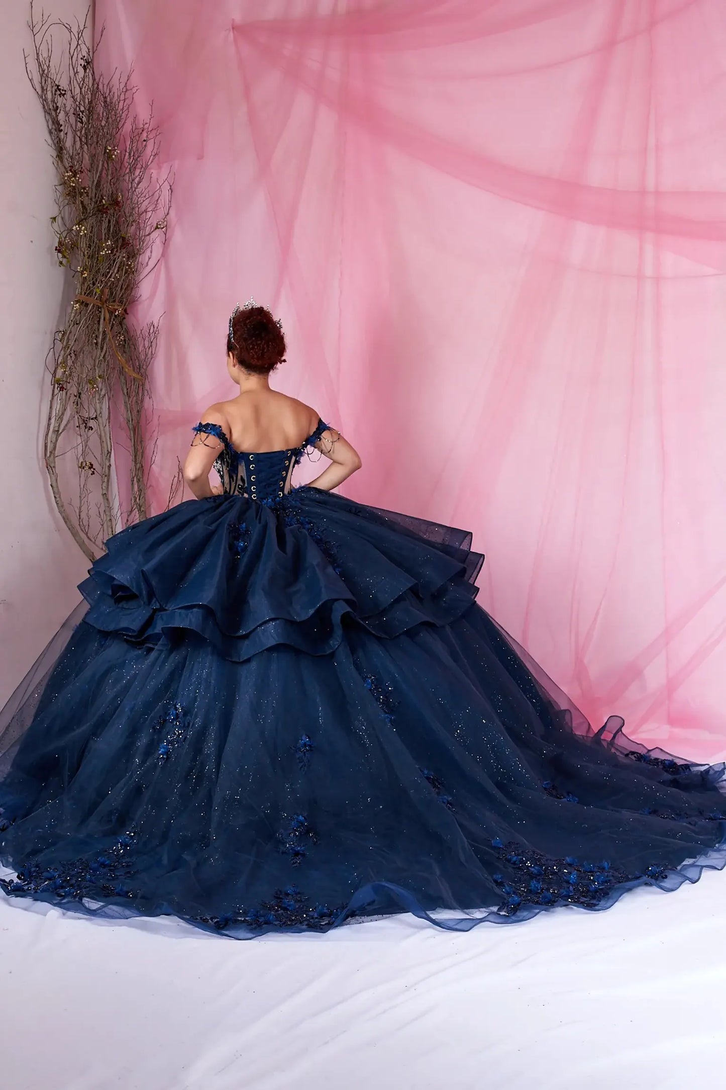Navy quinceanera ball gown with layered skirt, lace-up corset, bead accents, and chapel-length train