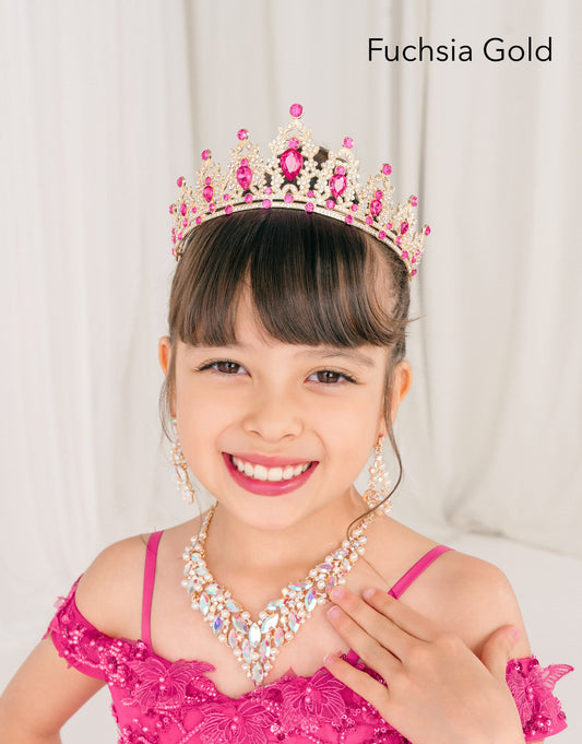 Young girl in a pink dress with a fuchsia gold tiara and necklace, against a plain background.