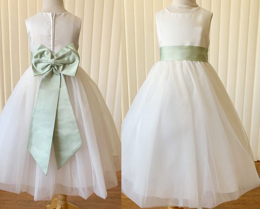 Two white dresses with green sashes on mannequins against a neutral background
