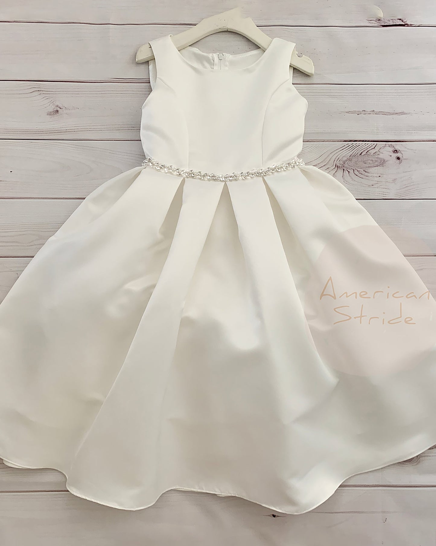 White satin dress with a beaded waistband on a wooden surface, branded 'American Stride'.