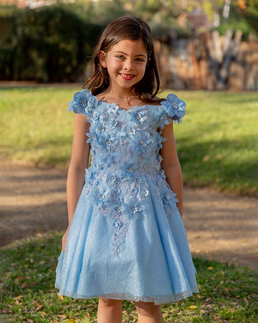 Young girl wearing a light blue floral dress outdoors.