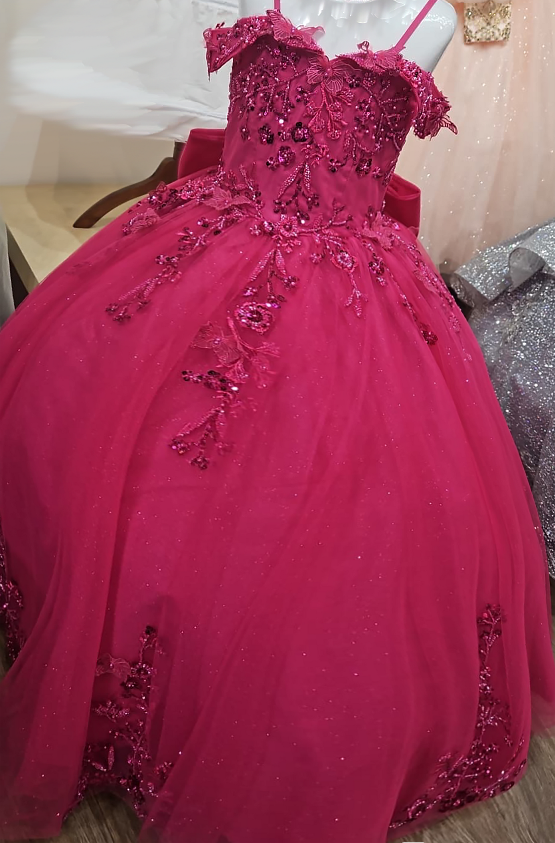Fuchsia gown with intricate detailing on a mannequin against a neutral background