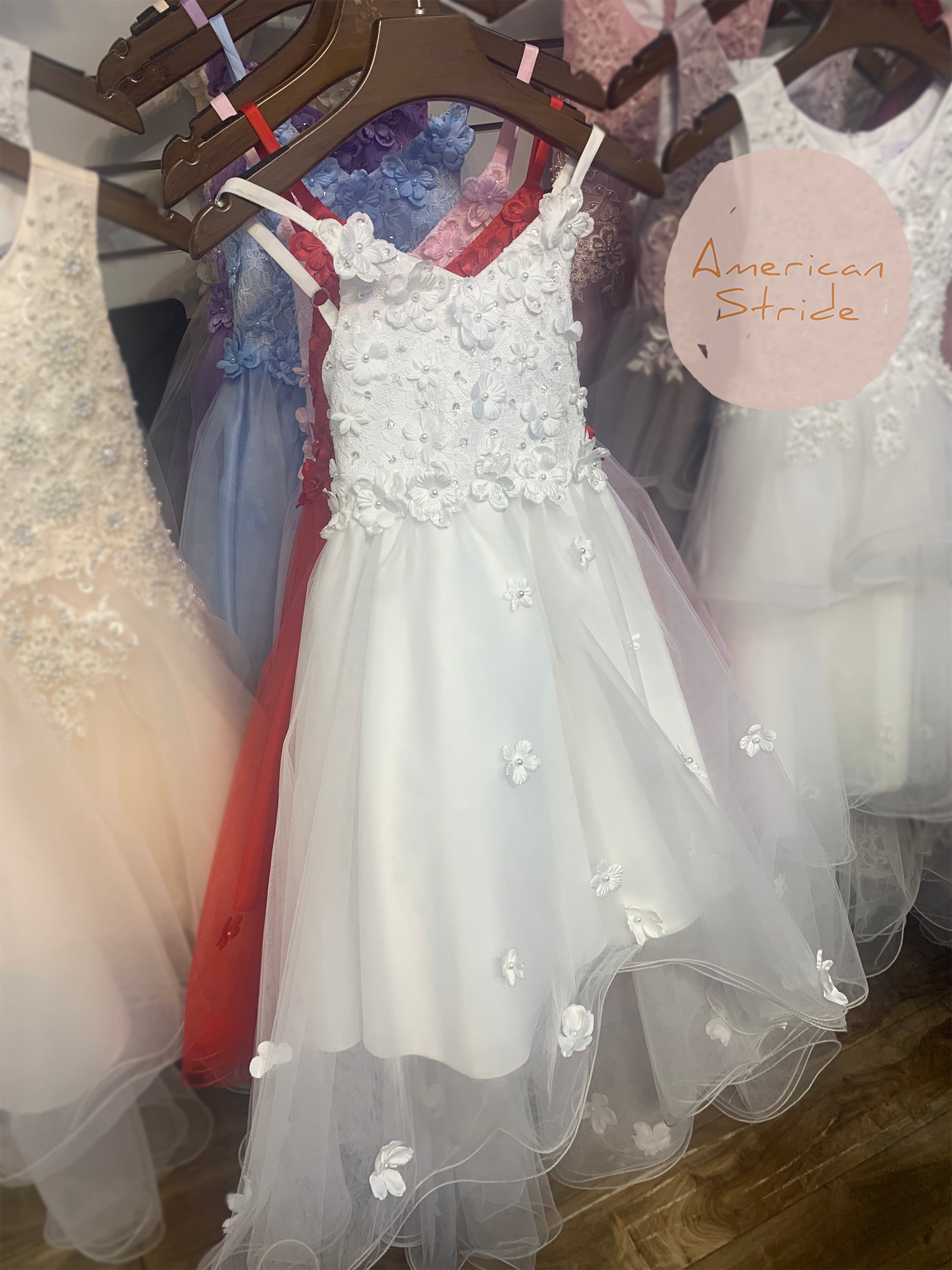 White High-Low Tulle Dress with Embedded 3D Floral Design | Flower Girl Dress - front view of different color dresses on hangers