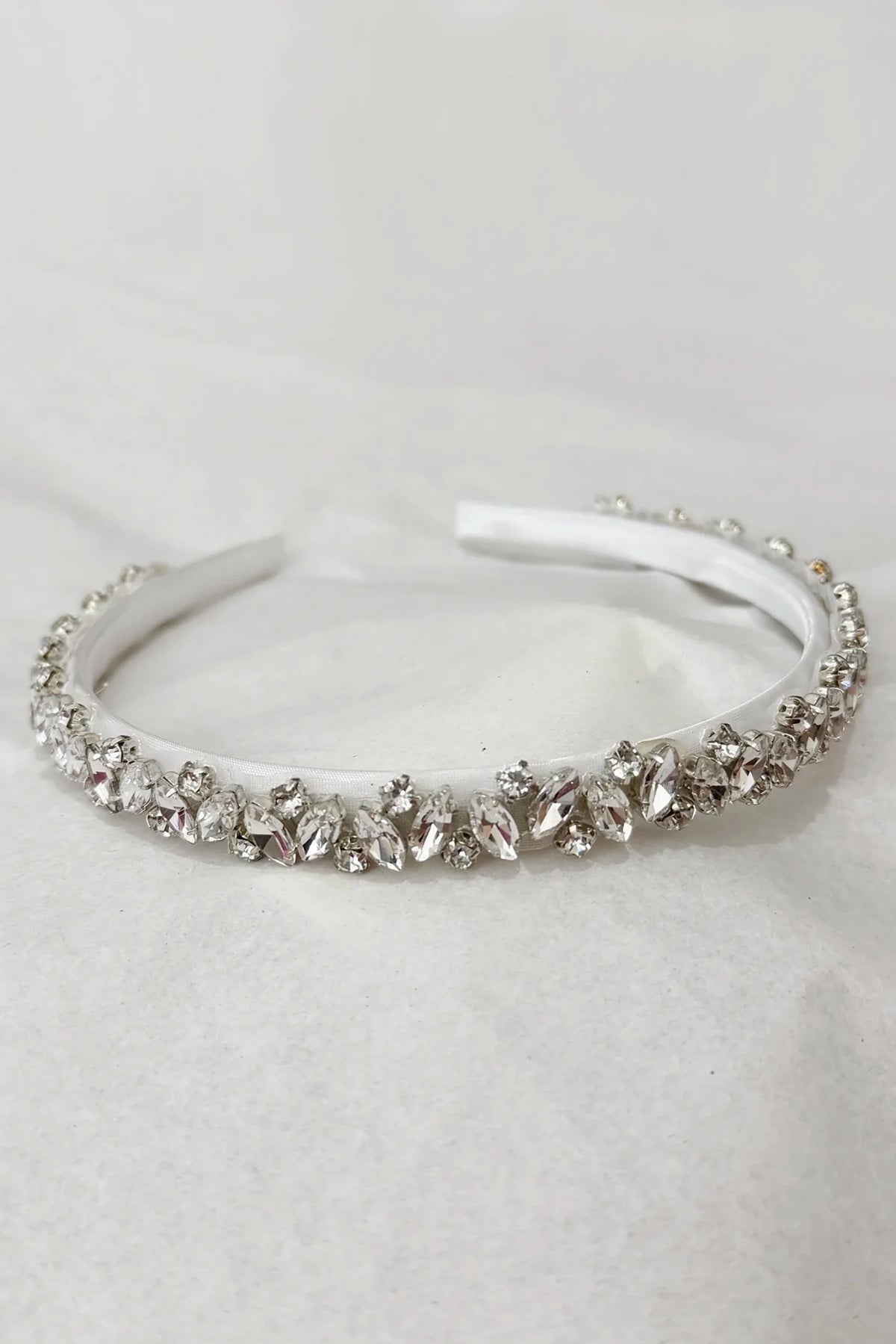A white fabric headband embellished with a row of clear rhinestones and crystal beads