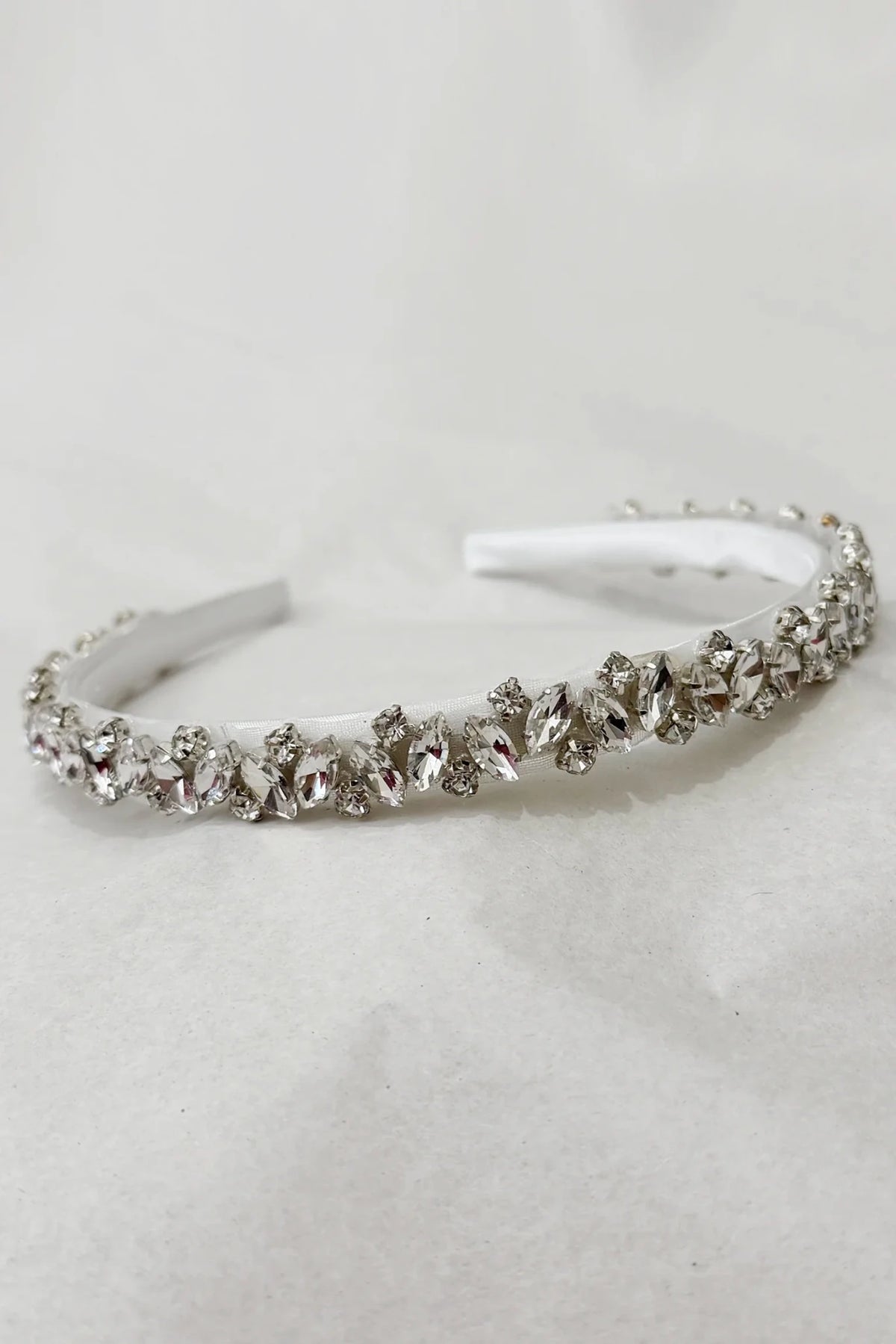A silver-toned kids headband embellished with a row of clear faceted rhinestones
