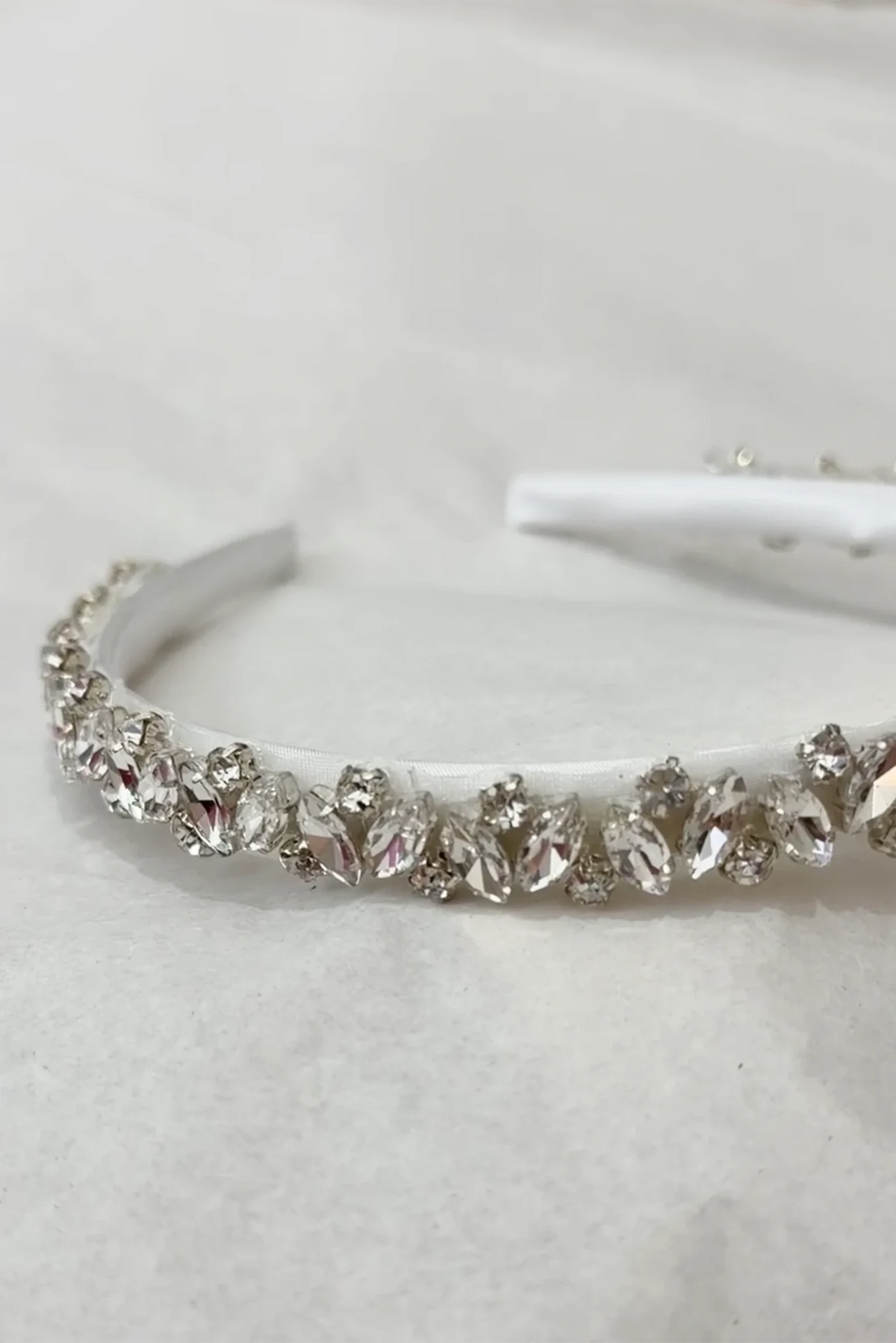 A white headband embellished with a row of sparkling clear rhinestones and crystal beads