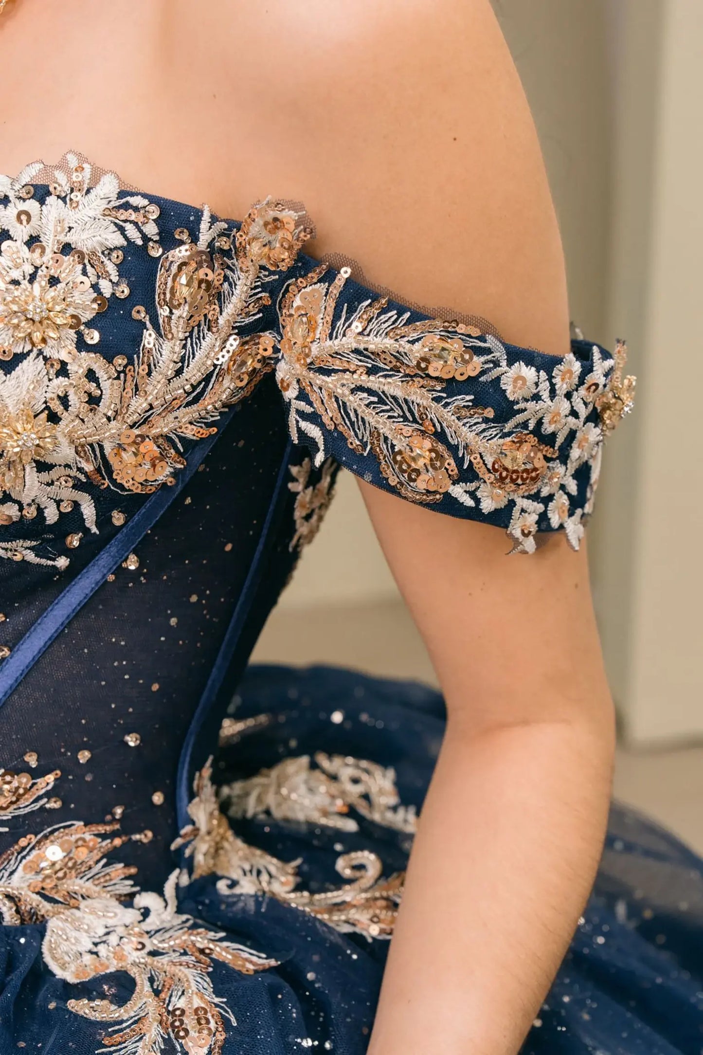 Close-up of arm detail navy quinceañera dress with gold embroidered corset bodice, sweetheart neckline, and shimmer tulle detailing