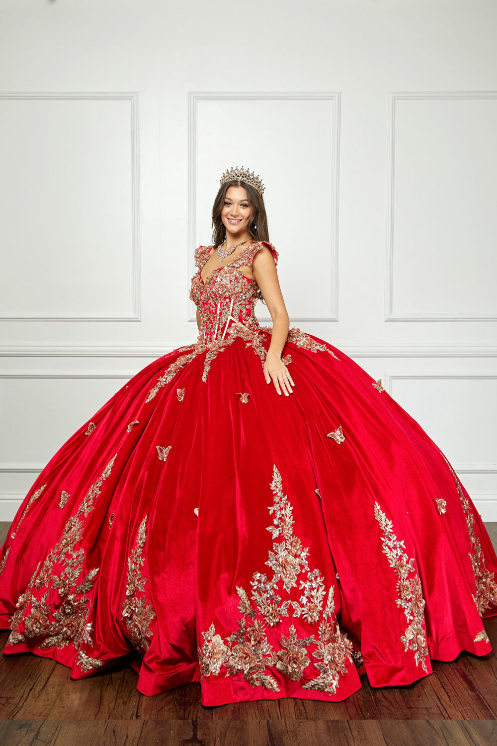 Red Quinceanera | Off-shoulder Velvet Sweetheart Gold Sequin sequin butterfly floral Ballgown with Sweep train - front/side view of woman wearing dress and crown smiling