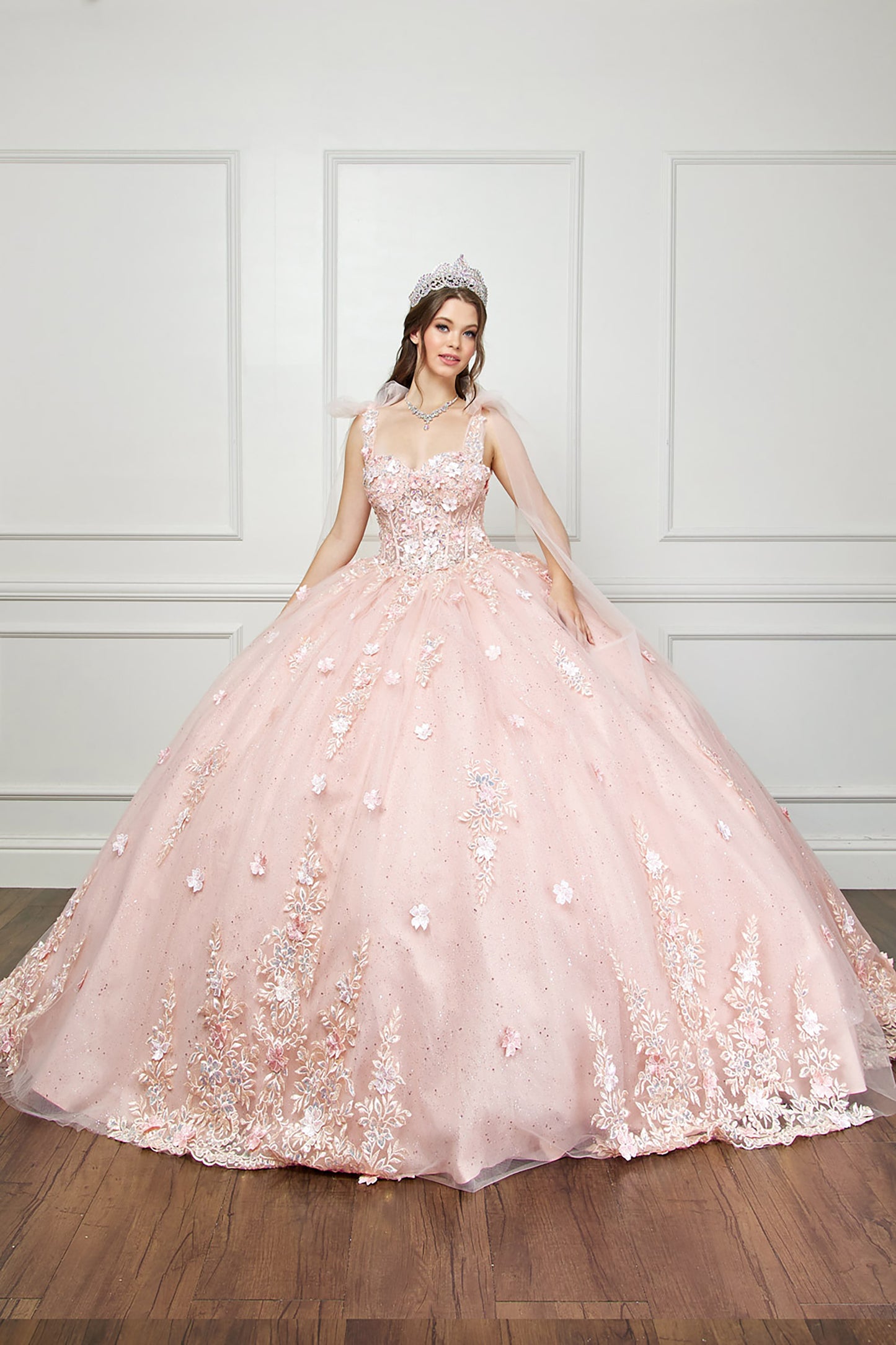 Quinceanera | Blush-Peach Flower Embroidery, Gem Detailing, and glitter lining Quince Ballgown with Tulle Shoulder Drape - full front view of woman wearing dress and crown with both hands at her sides