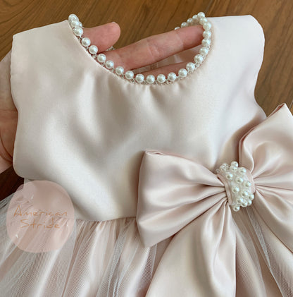 Blush USA Made | Pearl Neckline & Pearl detail Bow Satin and Tulle Flower Girl Dress - zoomed in view of hand holding up dress by pearl neckline