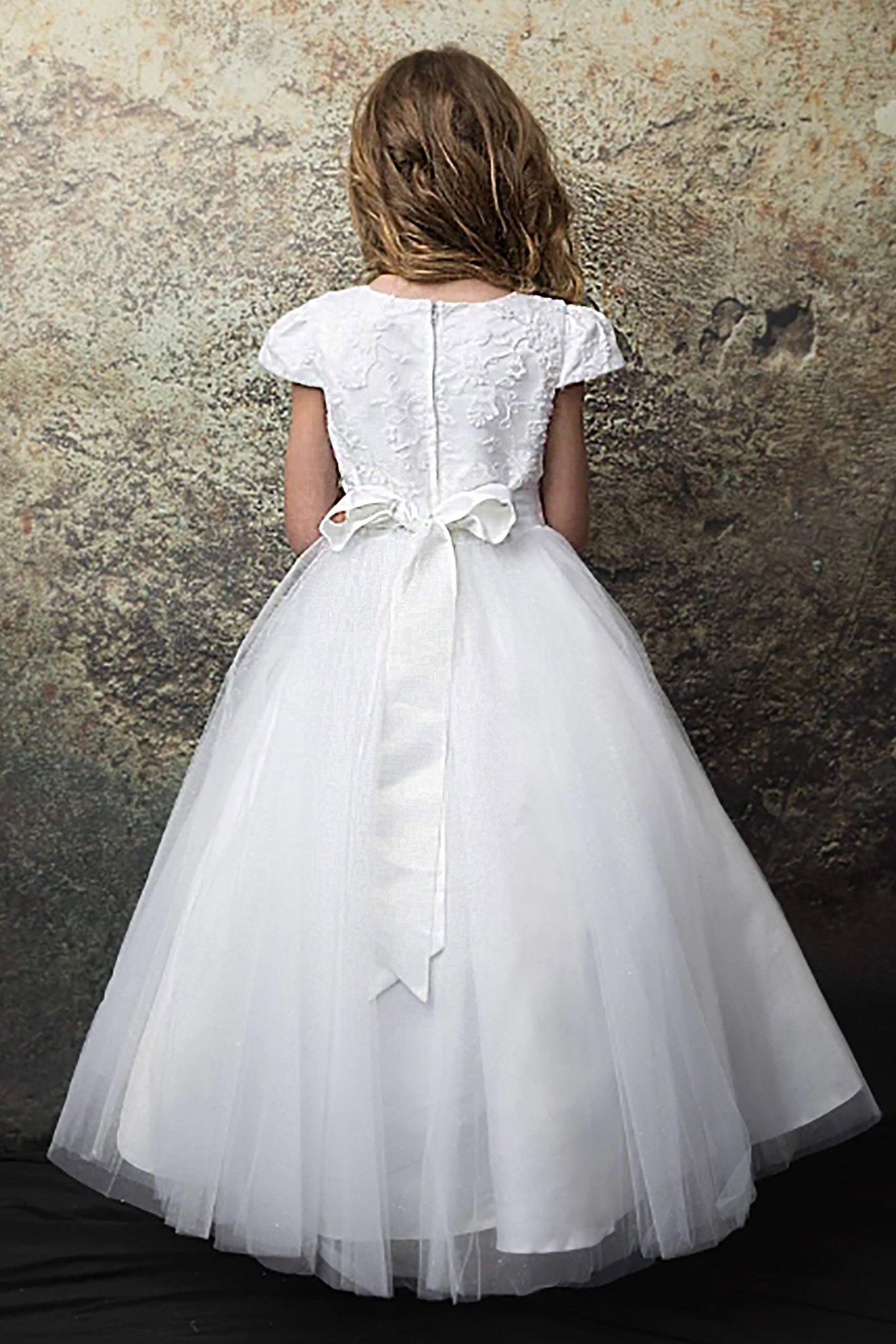 A white lace flower girl dress with a bow. Also suitable as a communion dress.
