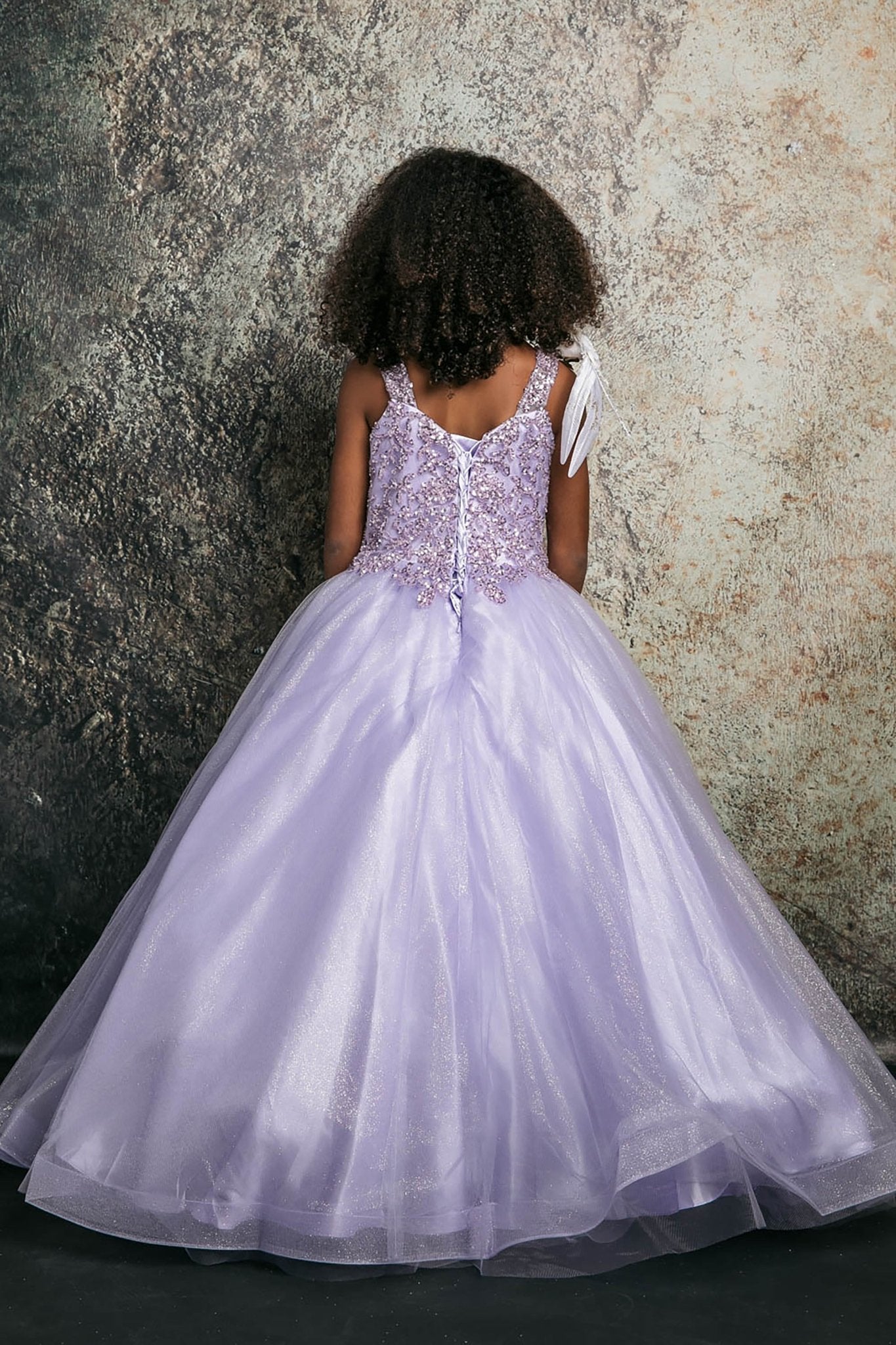 Back view of a lilac kids mini quinceanera mini quince dress with lace-up corset, oversized bow, sequin beaded bodice, and glitter tulle train.