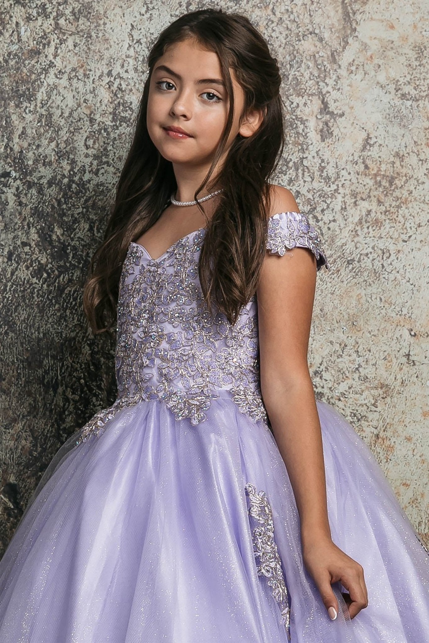 Side close up view of a lilac kids mini quinceanera mini quince dress with off-shoulder embroidered bodice, floral appliques, and layered tulle skirt.