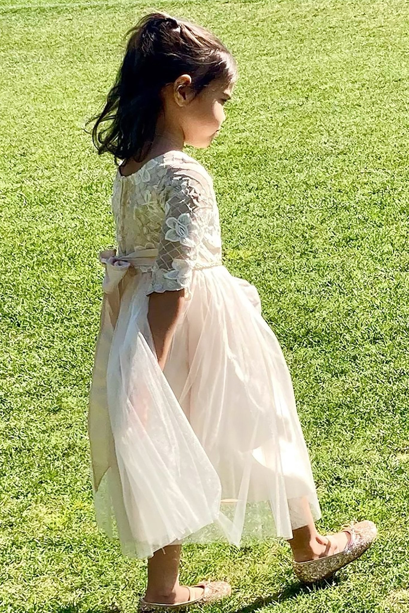 Young girl in a champagne dress standing on grass
