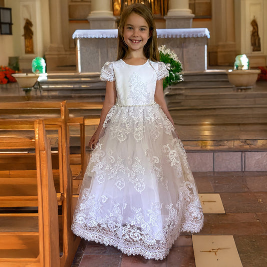 Young girl in a white lace dress standing in a church.