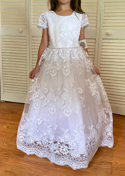 White lace dress worn by a person in front of a wooden door.