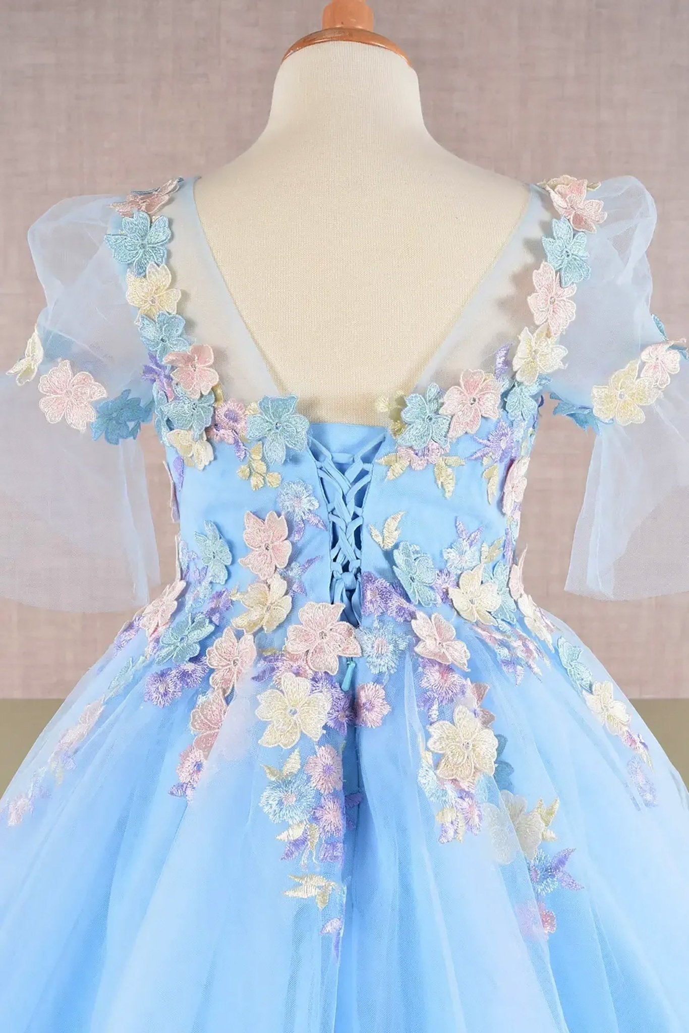 Back zoom view of a baby blue kid ballgown highlighting 3D floral applique, puff sleeves, and lace back up