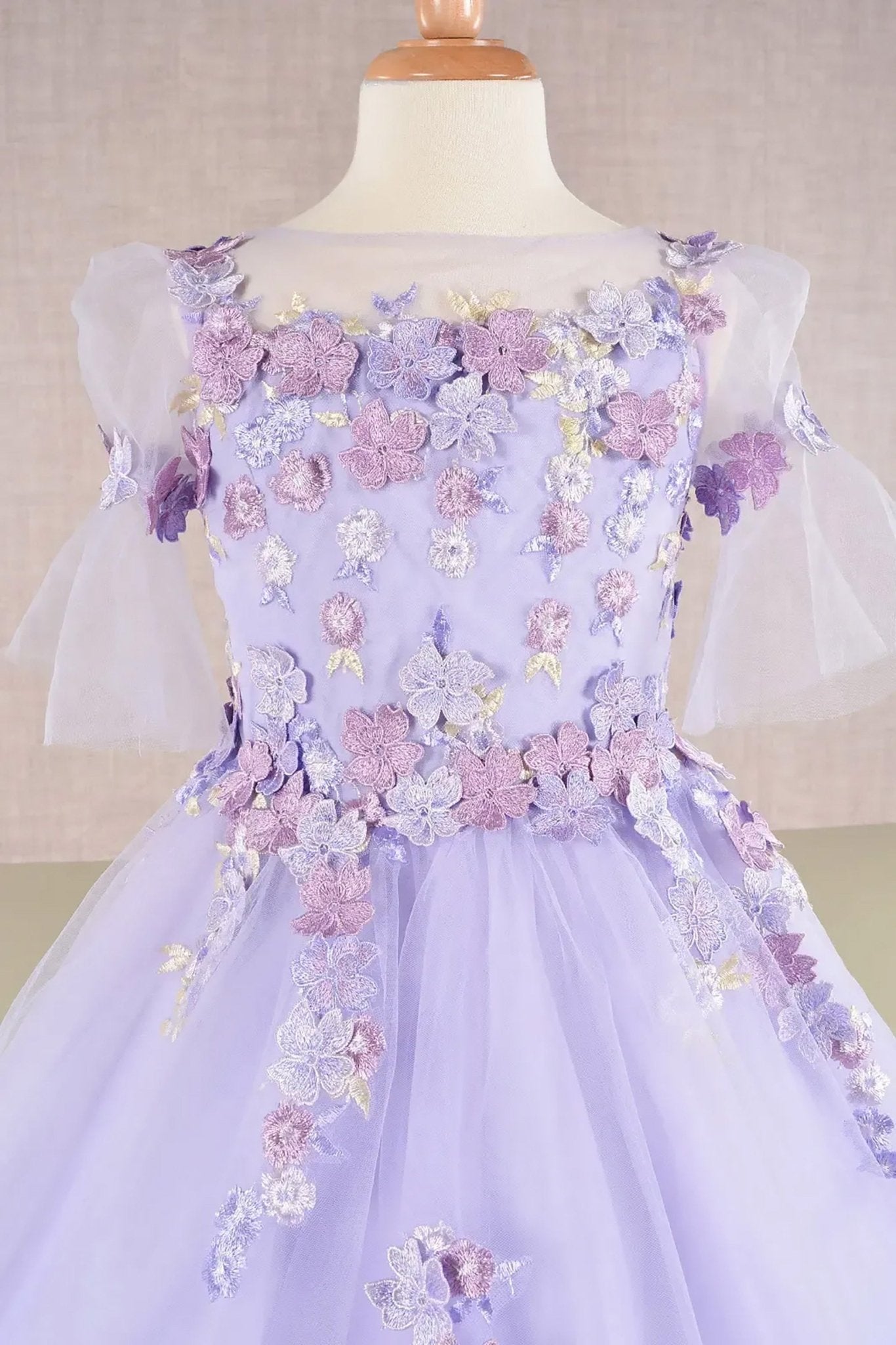 Front zoom view of a lilac kid ballgown with 3D floral applique, puff sleeves, and glitter tulle details
