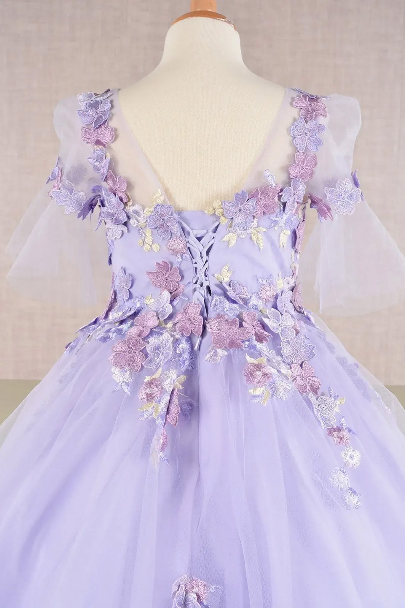 Back zoom view of a lilac kid ballgown showcasing floral appliques and extended back hem