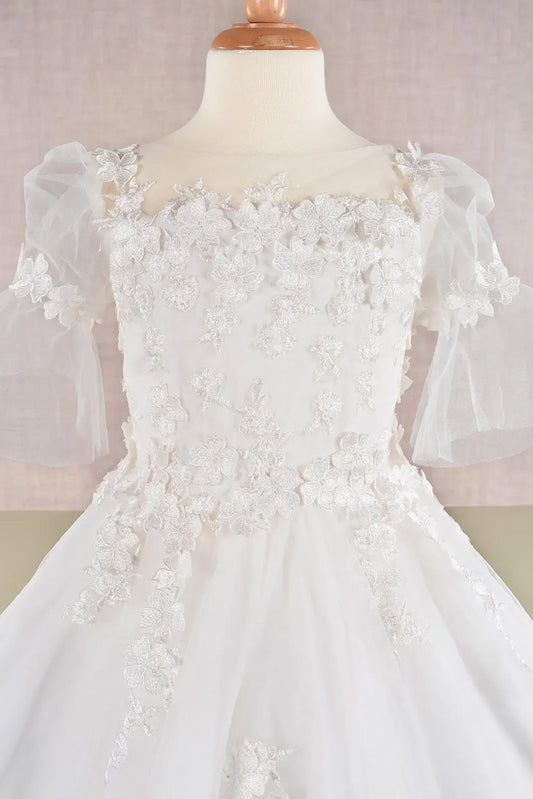 Detail view off-white kids mini quinceañera flower girl dress highlighting 3D floral appliques, mesh overlay and puff sleeve design. Also suitable as a mini quince dress. Also suitable as a communion dress.