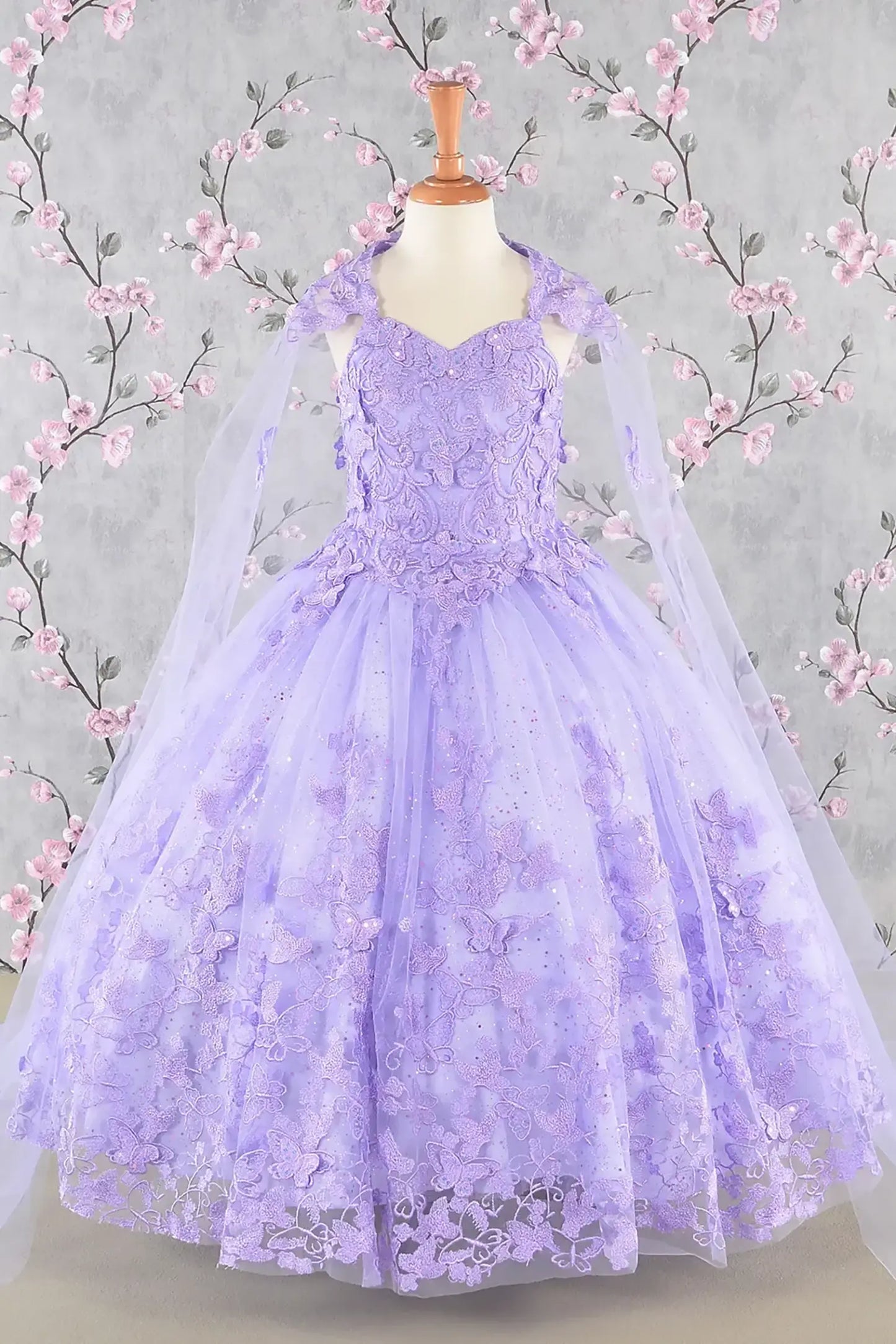 Front view of lilac kids mini quinceañera dress with 3D butterfly appliques, sequin-embellished bodice, glitter tulle skirt, and flowing mesh cape