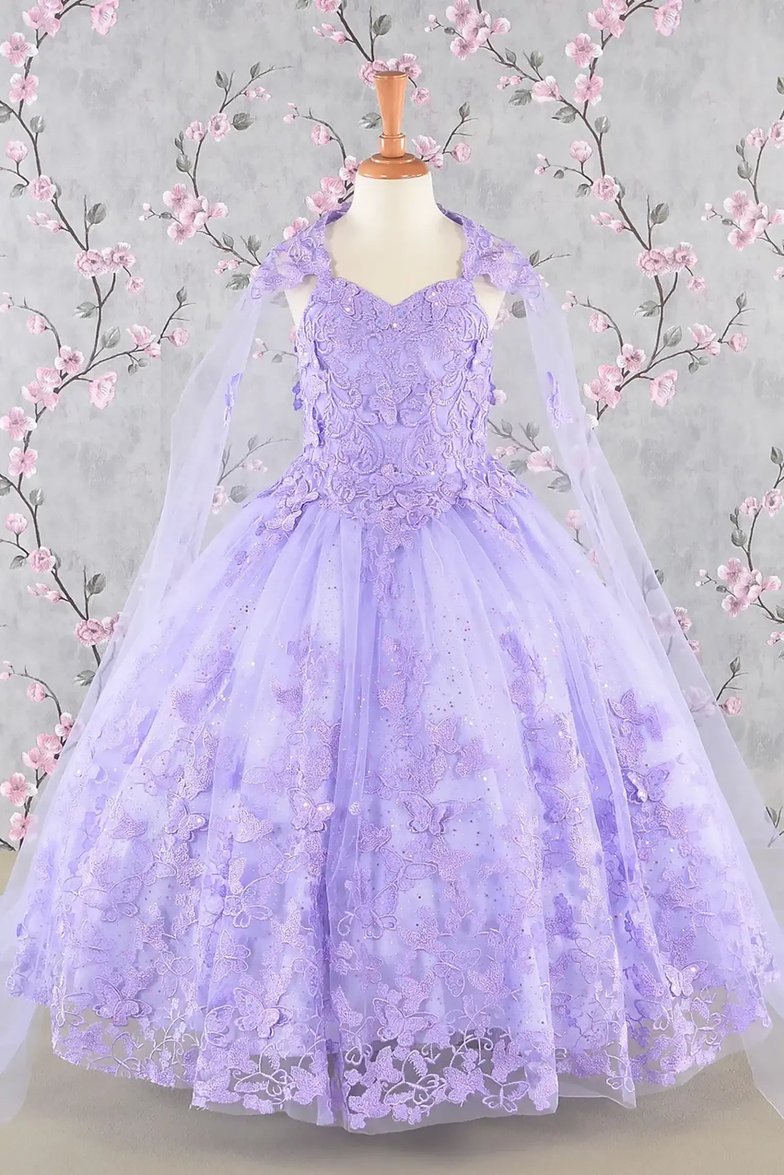 Front view of lilac kids mini quinceañera dress with 3D butterfly appliques, sequin-embellished bodice, glitter tulle skirt, and flowing mesh cape