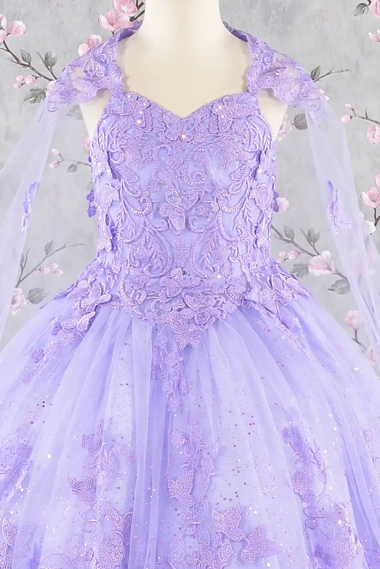 Front zoom view of a lilac kids ball gown with 3D butterflies, sequins, and detachable mesh cape
