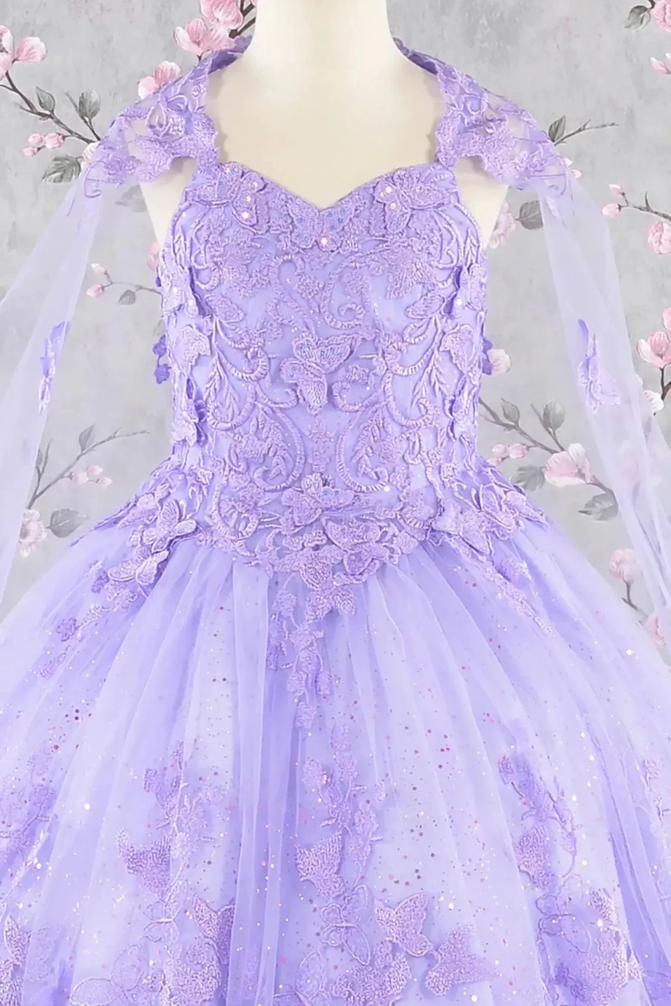 Front zoom view of a lilac kids mini quince dress with 3D butterflies, sequins, and detachable mesh cape.