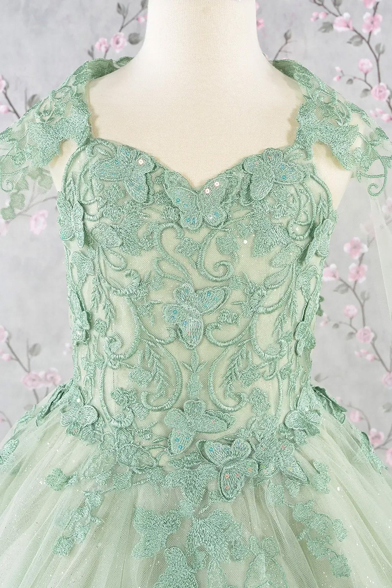 Zoom green lace mini quince dress highlighting lace texture and embellishments.
