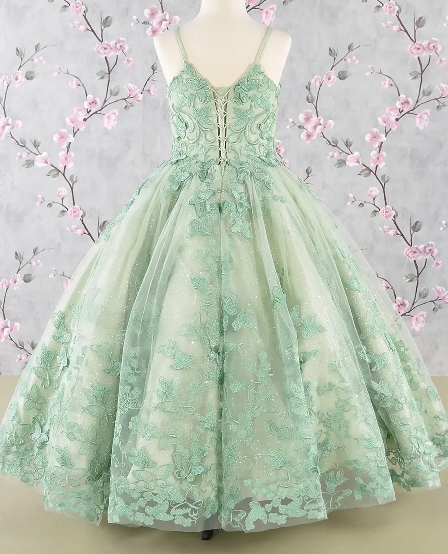 Sage green kids mini quinceañera mini quince dress with 3D butterfly appliques, sequin-embellished bodice, glitter tulle skirt, and flowing mesh cape.