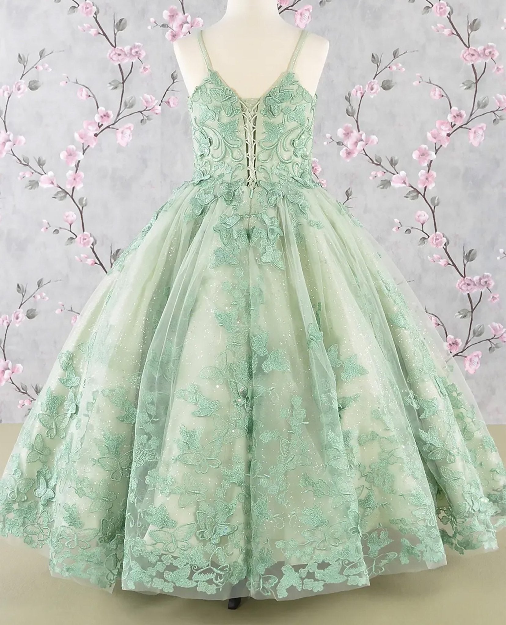 Sage green kids mini quinceañera mini quince dress with 3D butterfly appliques, sequin-embellished bodice, glitter tulle skirt, and flowing mesh cape.