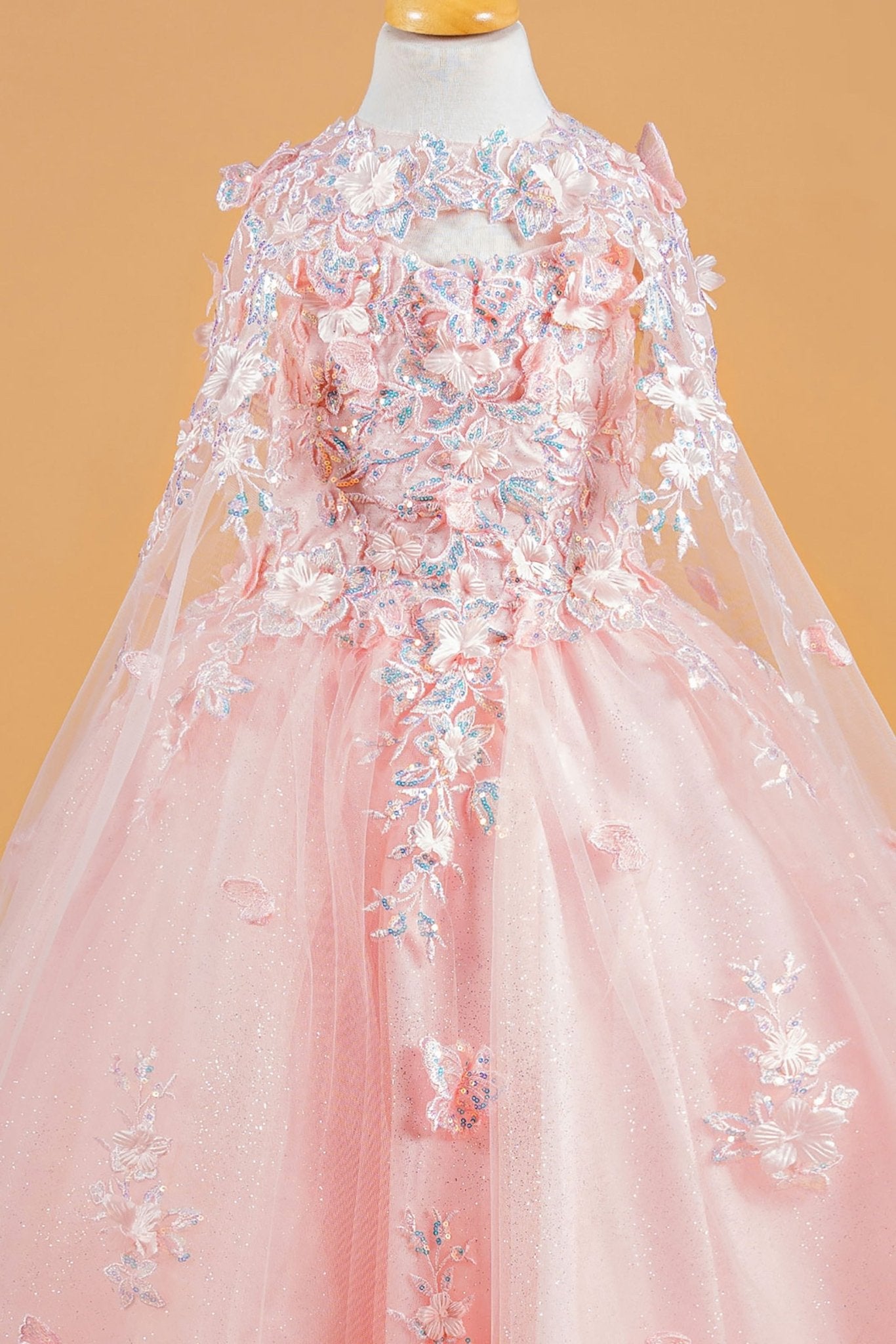 Front zoom view of a blush kids mini quinceañera mini quince dress with 3D flower and butterfly appliques and matching tunic.