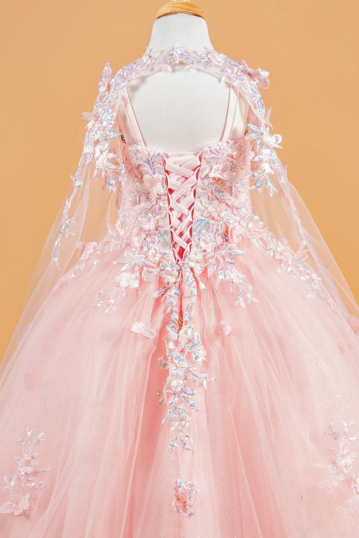 Back zoom view of a blush kids mini quinceañera mini quince dress showcasing 3D flower and butterfly appliques with matching tunic.