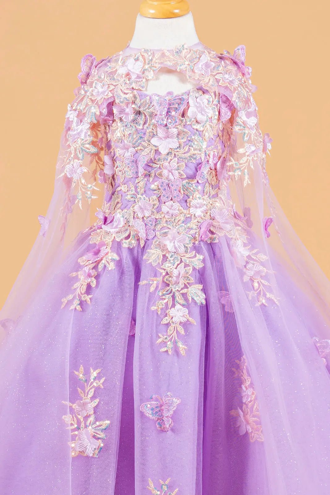 Lilac kids mini quinceañera mini quince dress with 3D flower and butterfly applique bodice, glitter tulle skirt, and sheer tunic overlay.