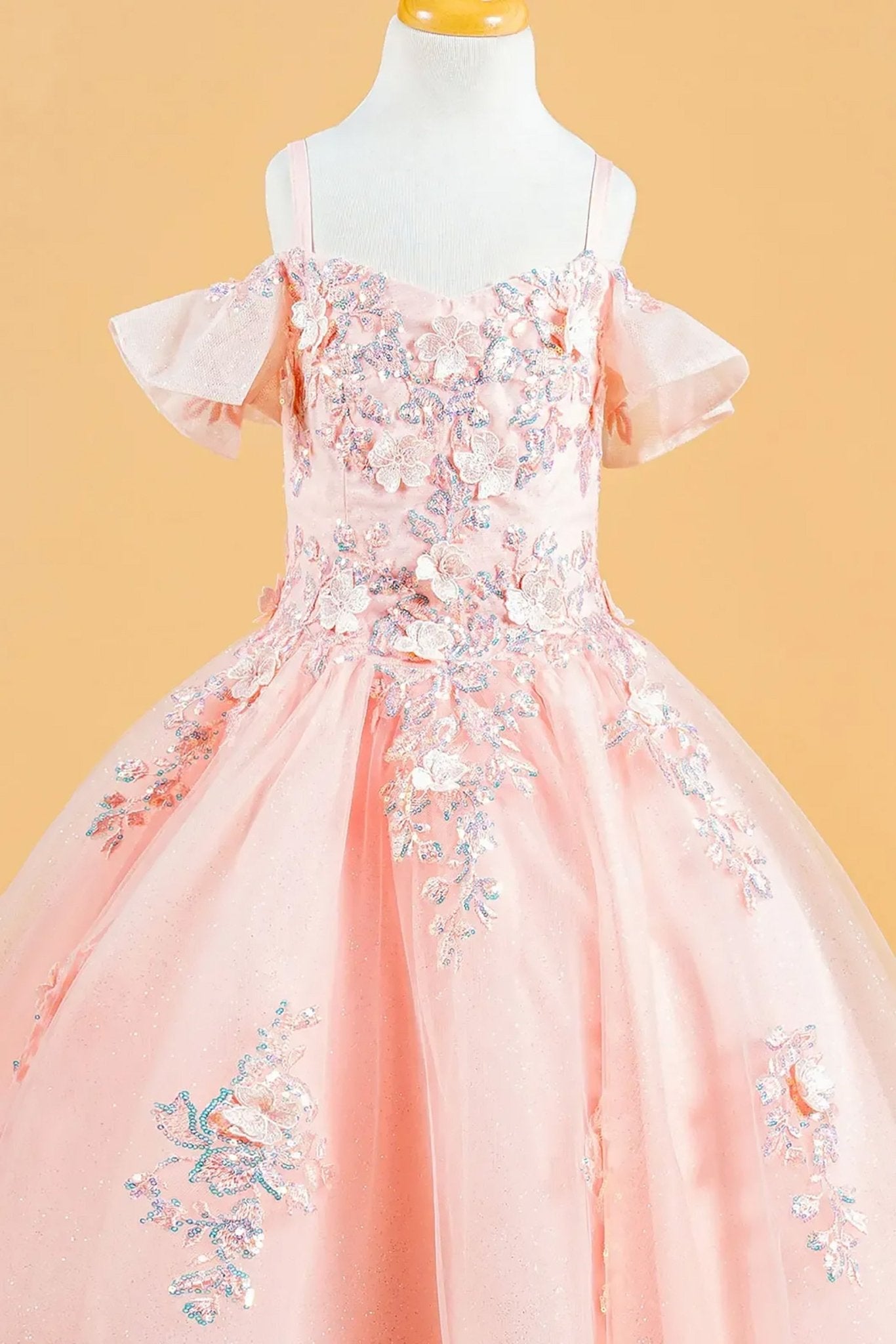 Front zoom view of a blush kids cold shoulder mini quince dress highlighting 3D flowers, sequins, and lace-up back.