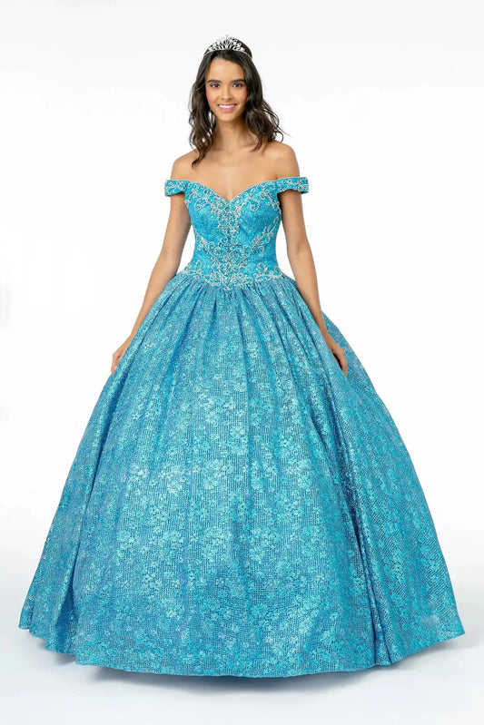 Sweeping Turquoise quinceañera ball gown is shown in full with an off-shoulder neckline and sparkling patterned ball skirt.