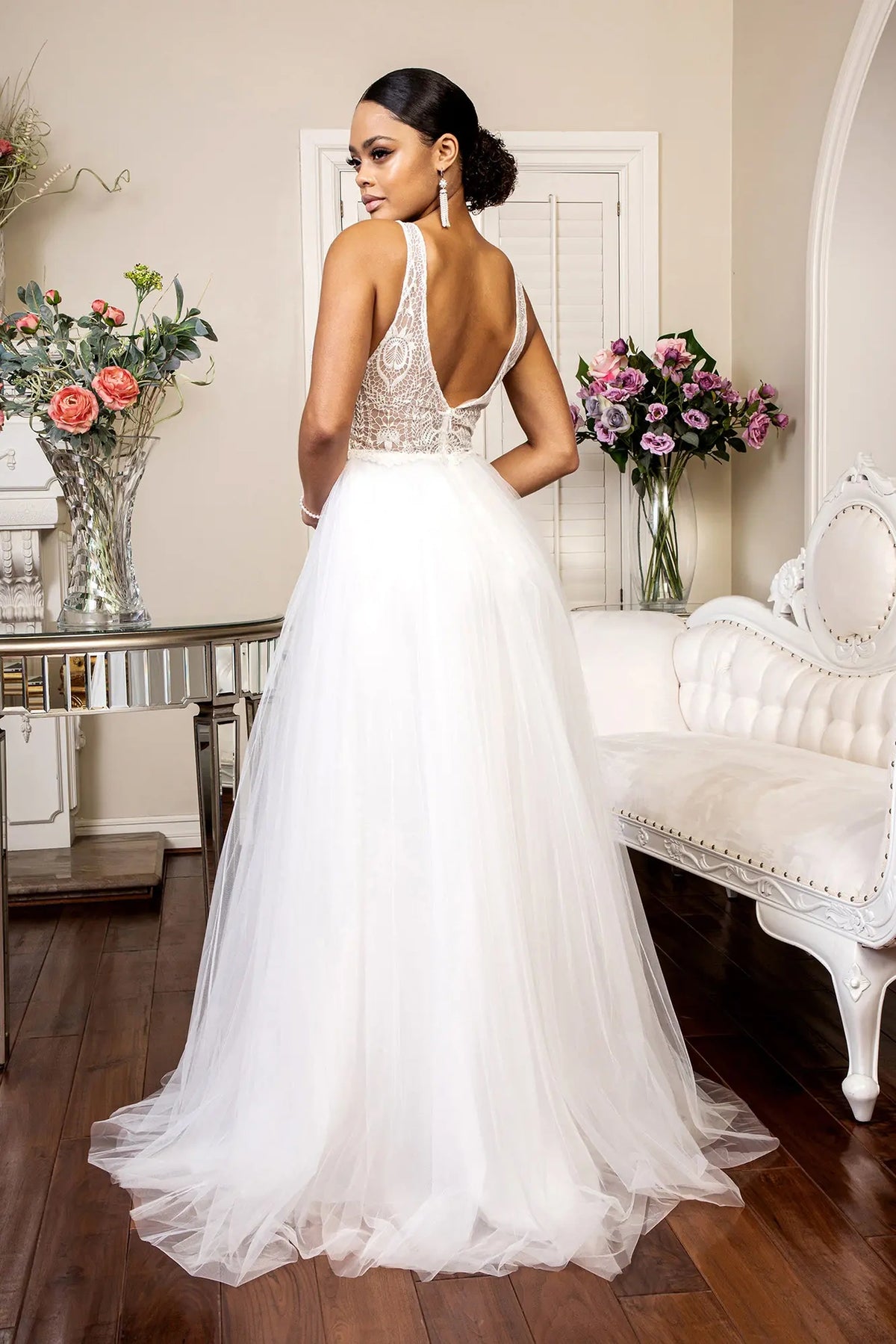 A wide V-back opens above the flowing skirt of this ivory wedding gown.