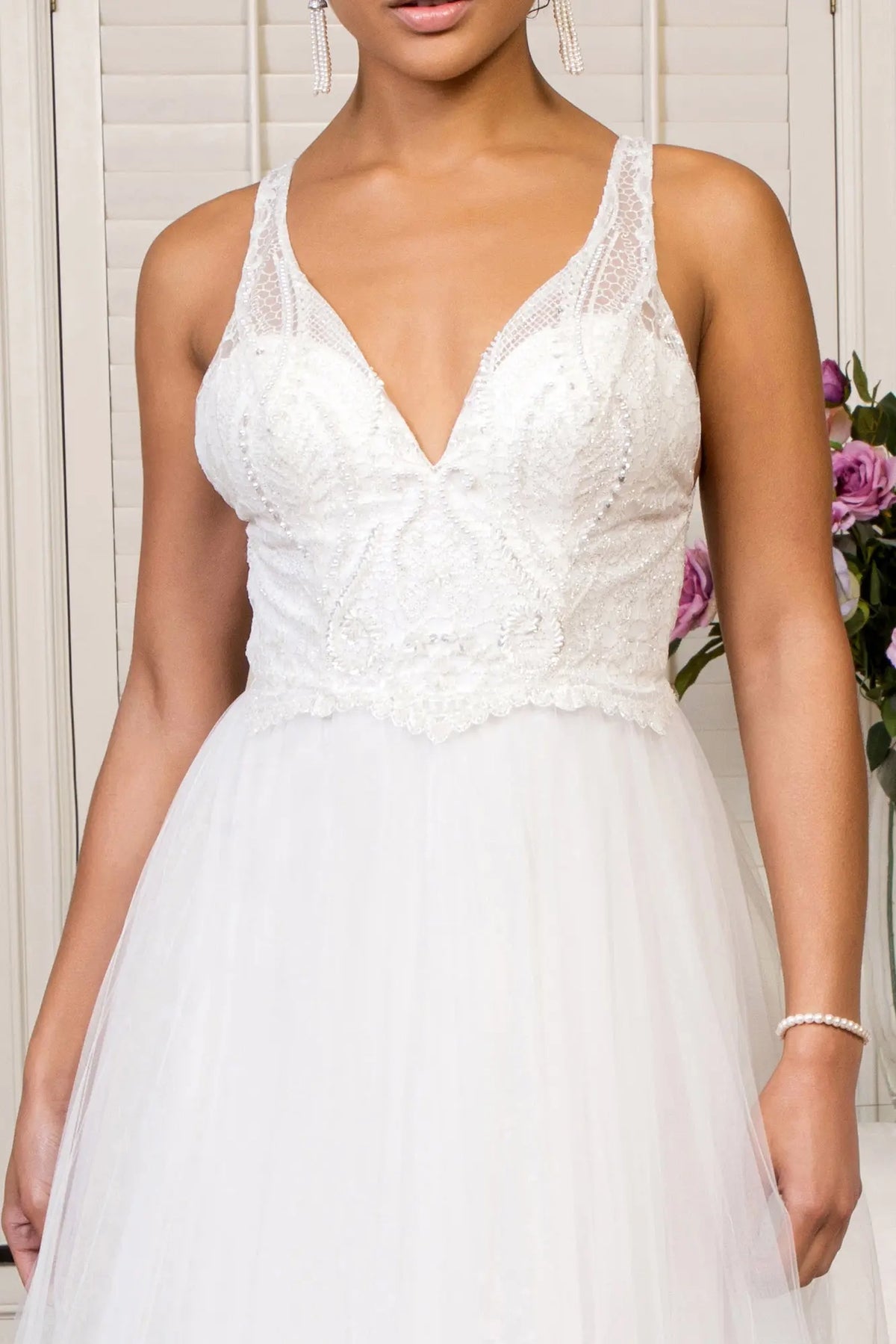 Delicate beadwork outlines the V-neck mesh bodice on the ivory wedding gown.