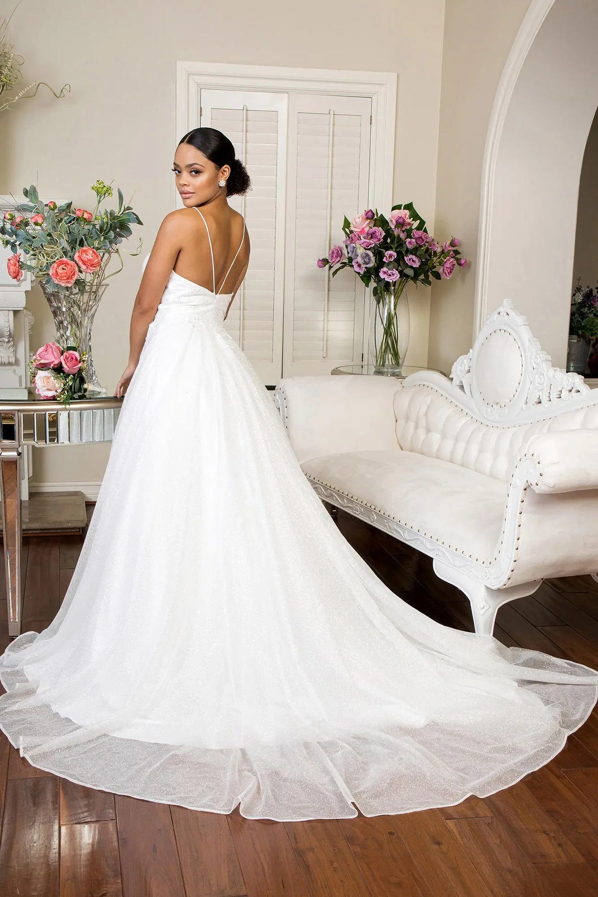 Crossing straps frame the open back above the train of the ivory wedding gown.