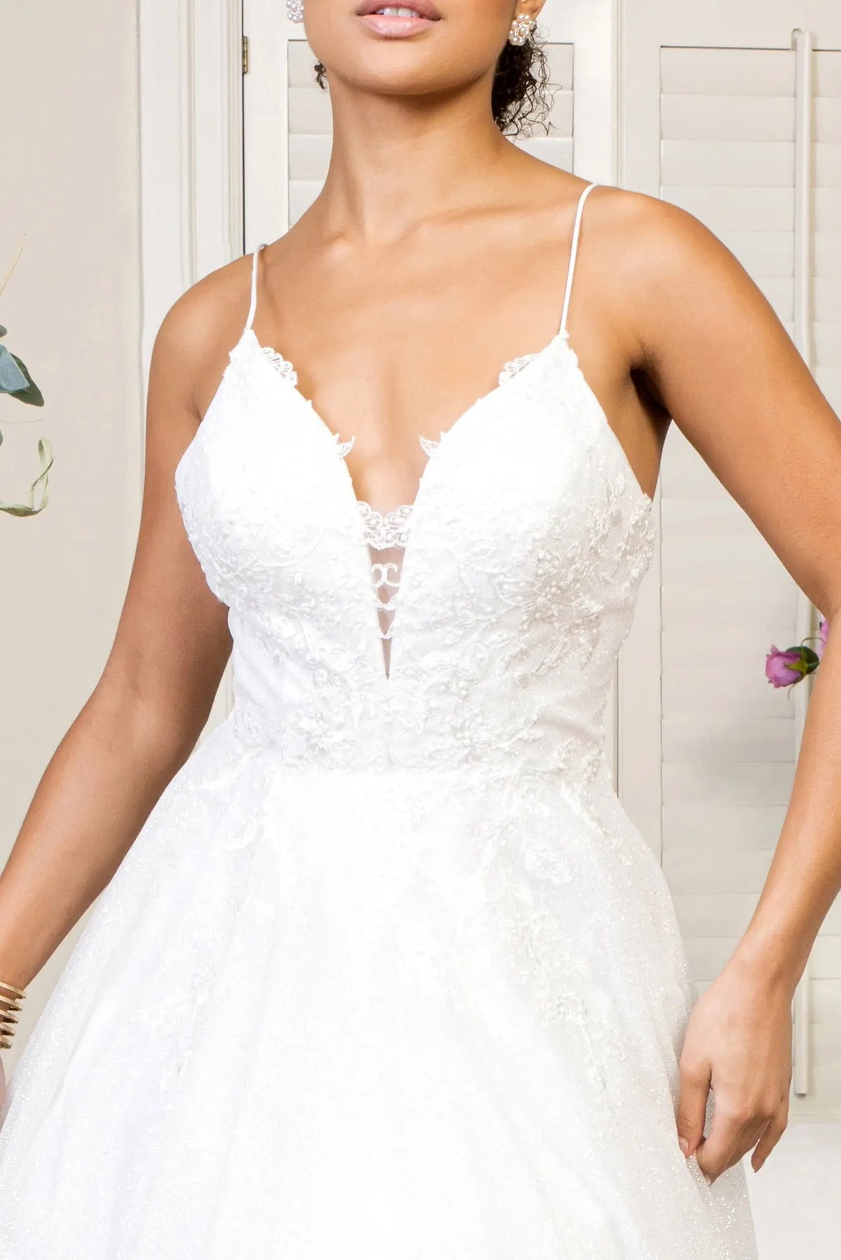 Beaded embroidery borders the plunging sweetheart bodice of this ivory wedding gown.