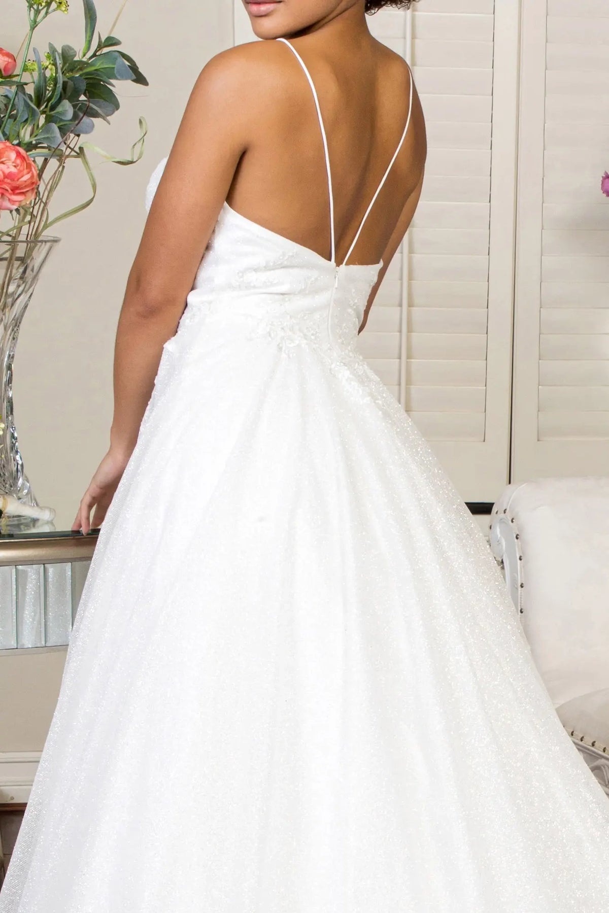 Slender double straps form a V across the open back of the ivory wedding gown.