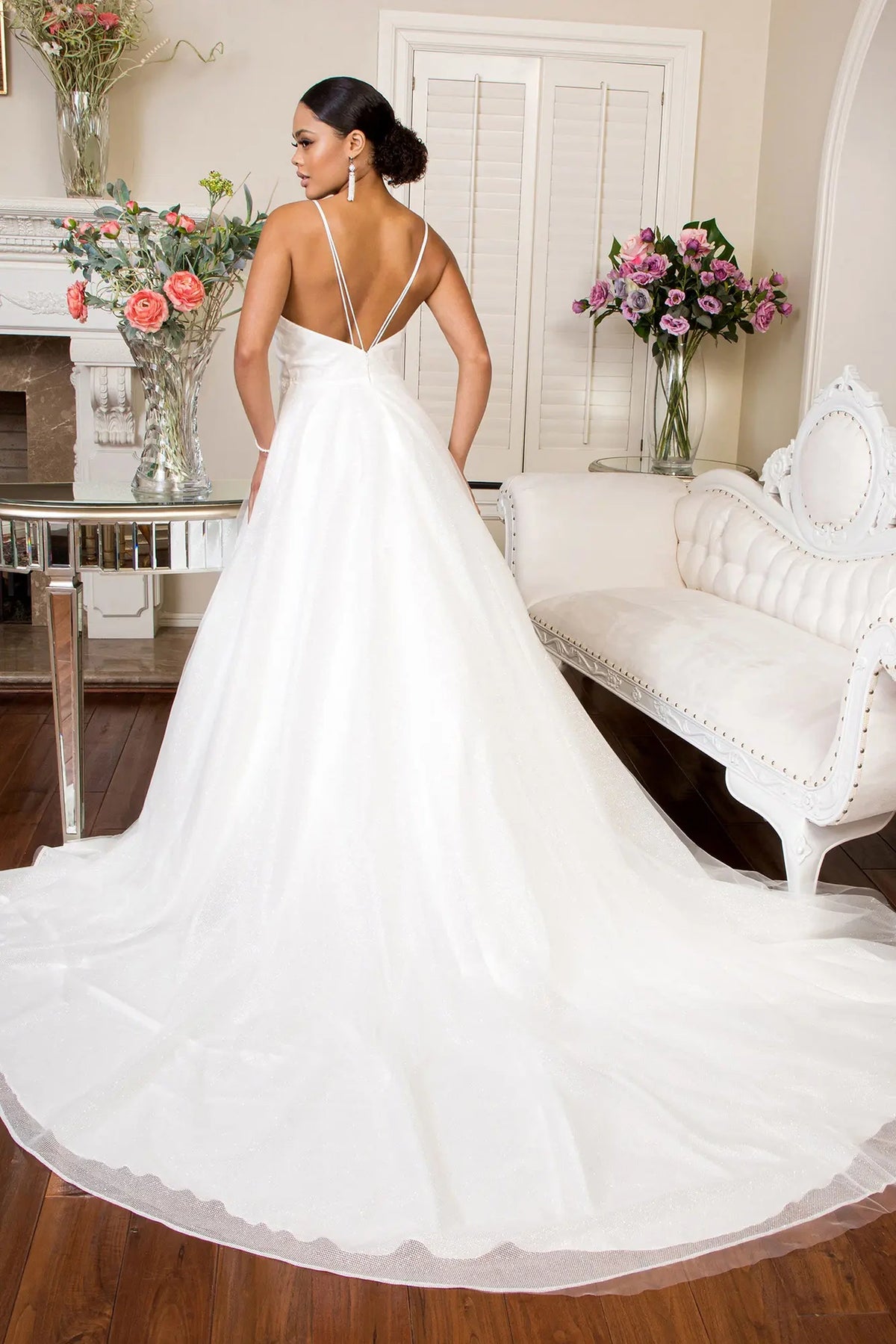 An airy train flows beneath the open strappy back of this ivory wedding gown.