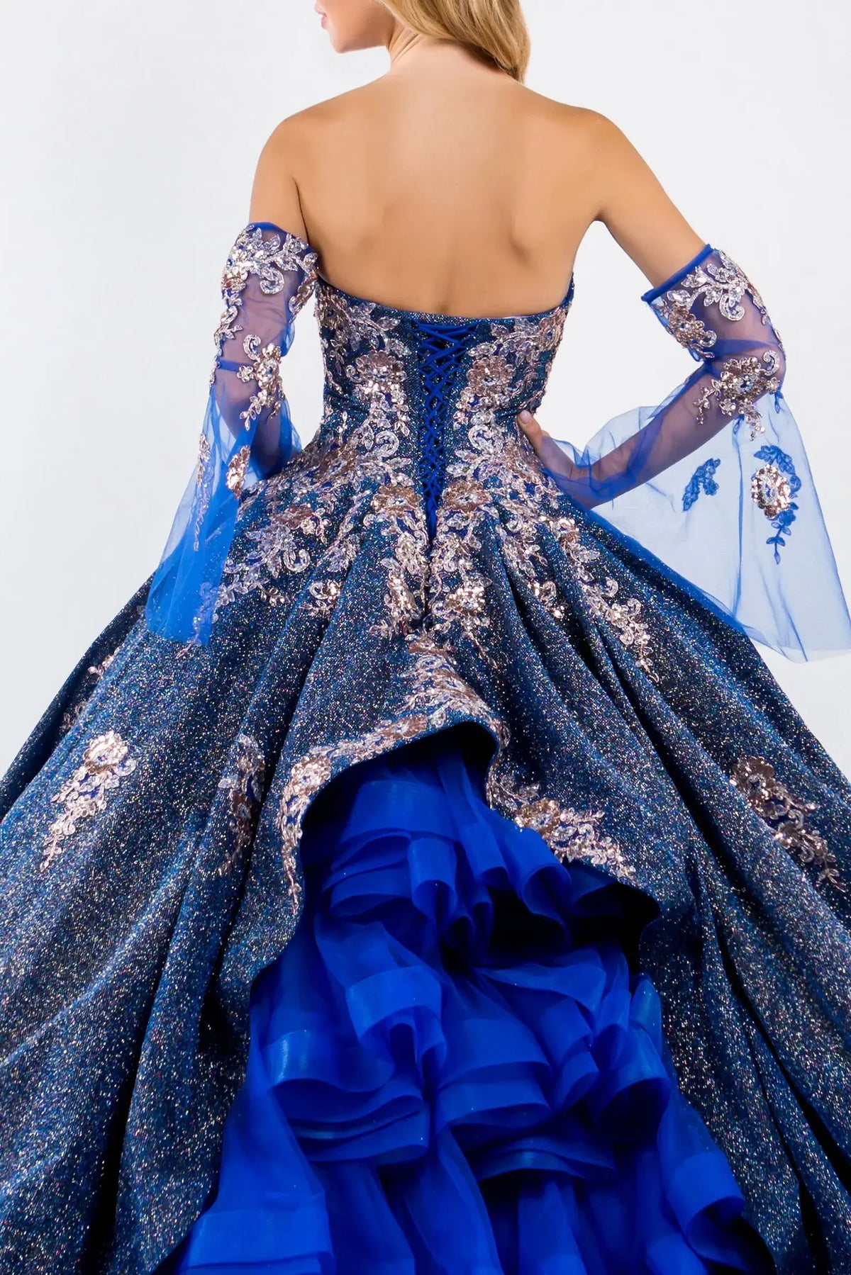 Embroidered details frame the Royal Blue quinceañera ball gown with ruffled train.