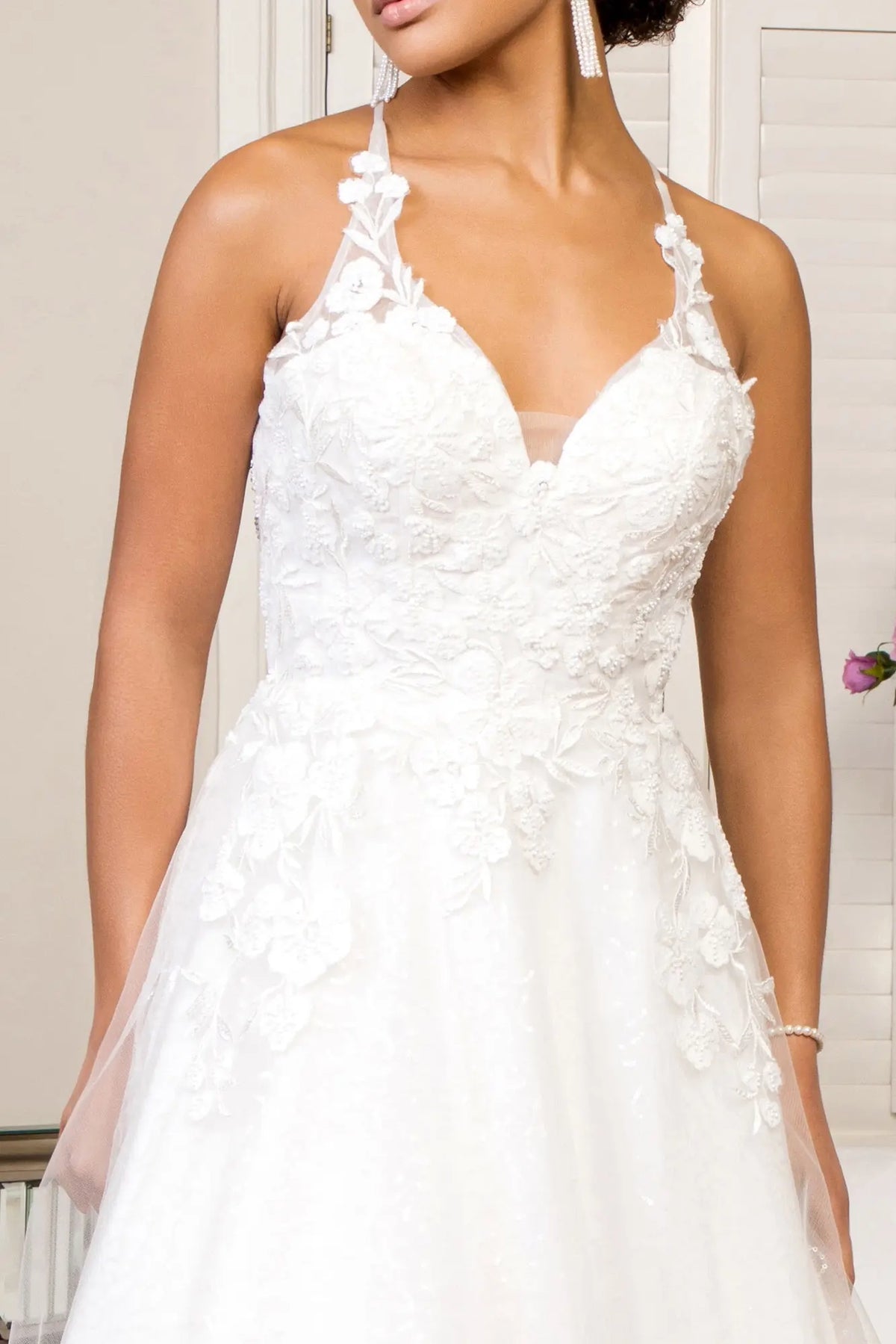 Floral appliques and beading highlight the illusion V-neckline on the white wedding gown.