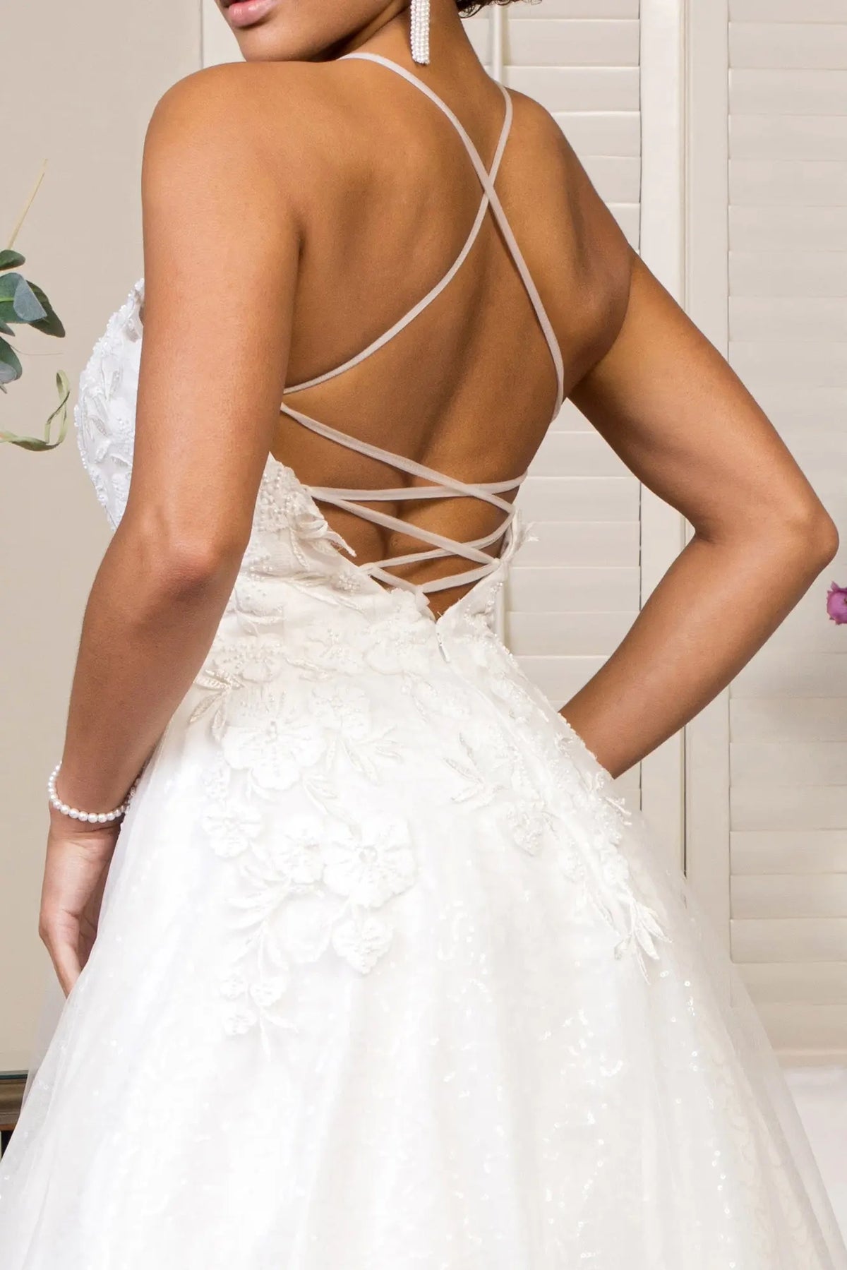 Fine straps weave across the open corset back of this white wedding gown.