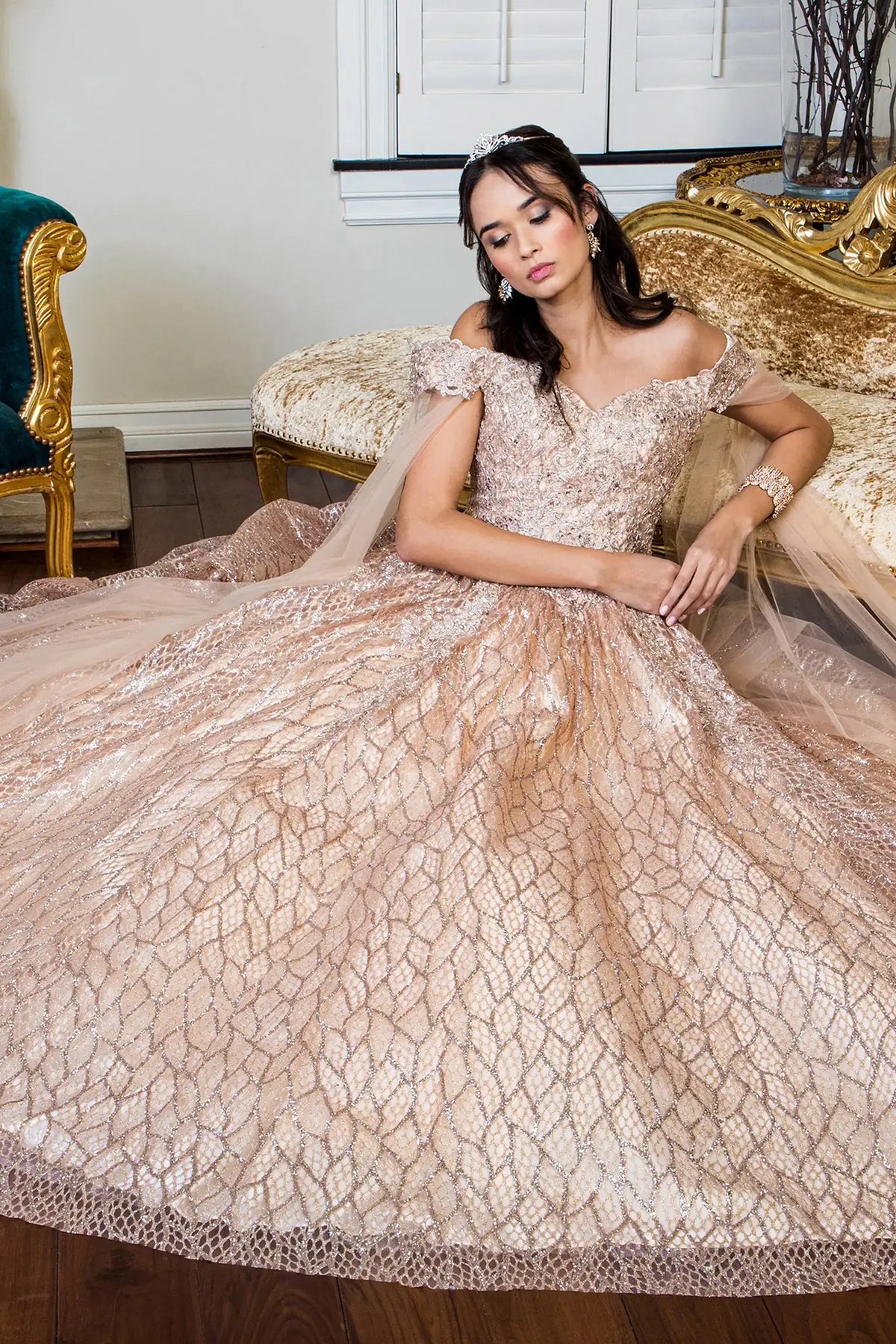 Layered skirt showcases the Gold quinceañera ball gown with cutaway shoulder.
