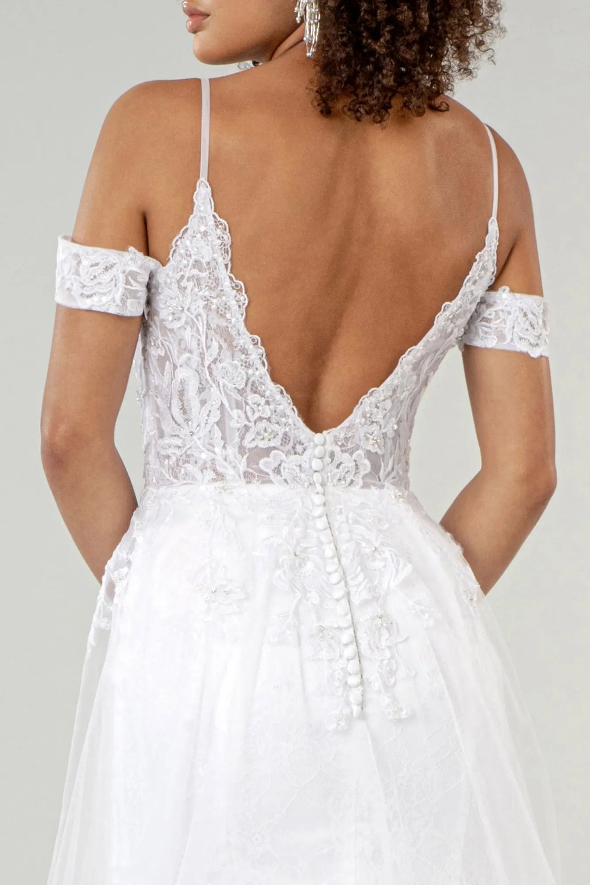 Buttons trace the sheer V-back above the lace waist of the white wedding gown.