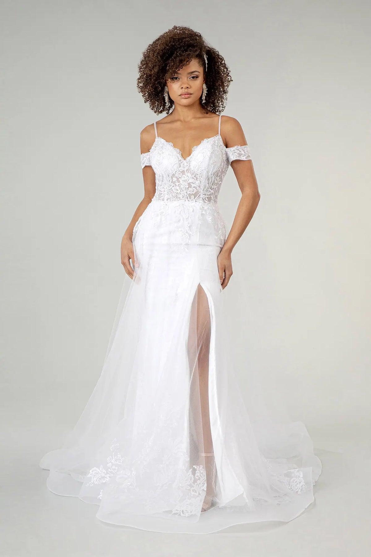 Embroidered mesh flows over the fitted inner silhouette of this white wedding gown.