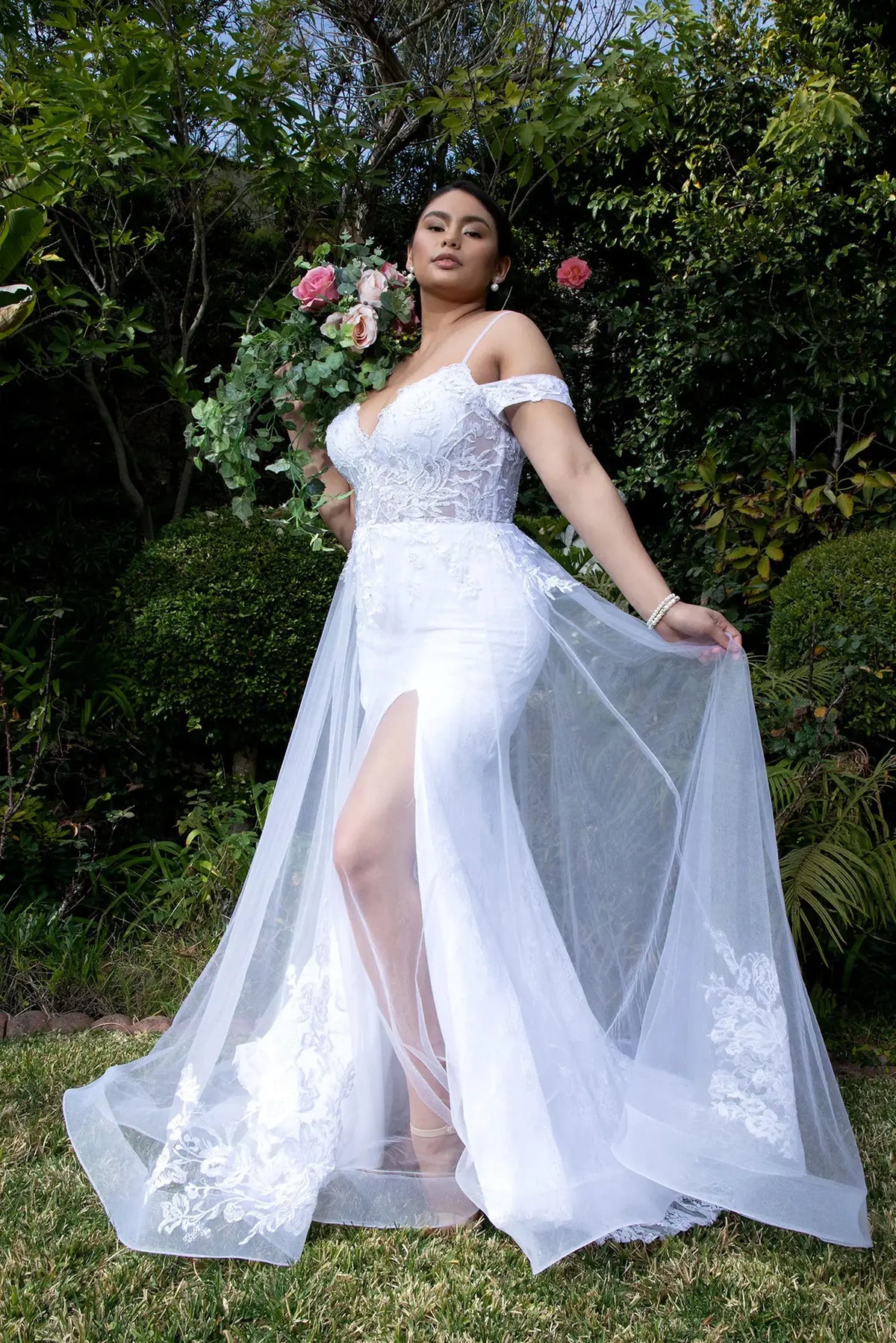 Floral embroidery falls through the layered A-line skirt of this white wedding gown.
